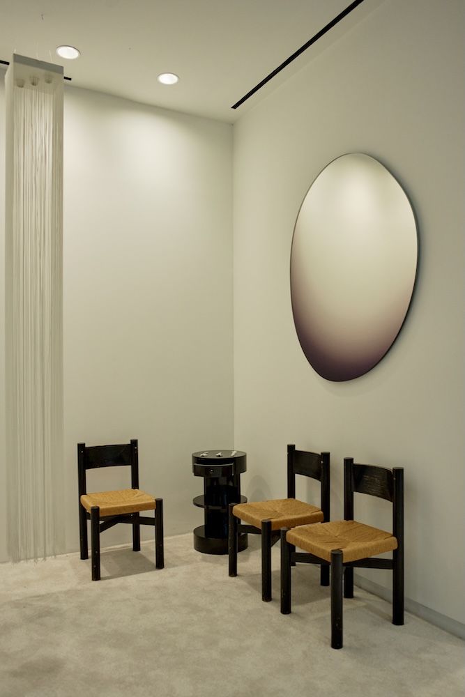 Mirror on the wall with three chairs and a side table 