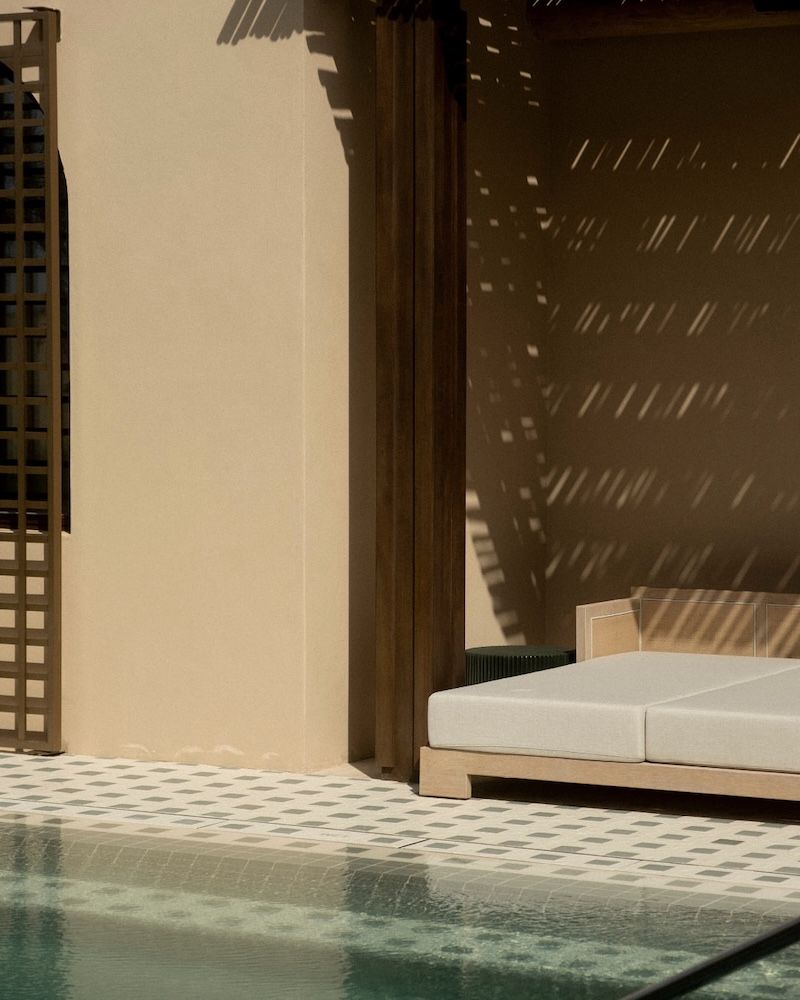 Pool in foreground with lounger in background and shadow play