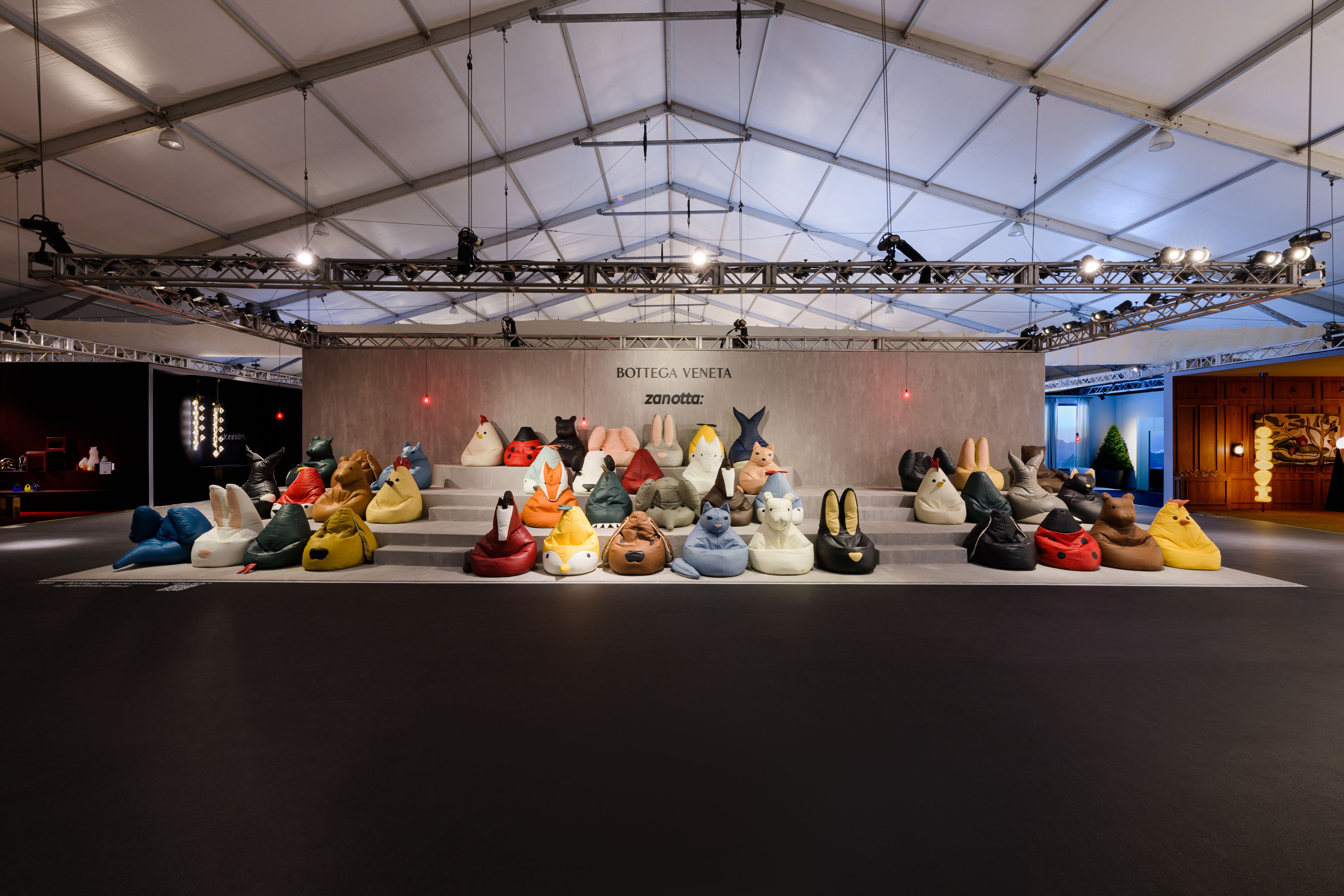 Colorful animal-shaped bean bag chairs by Bottega Veneta and Zanotta displayed on tiered platforms in an exhibition tent
