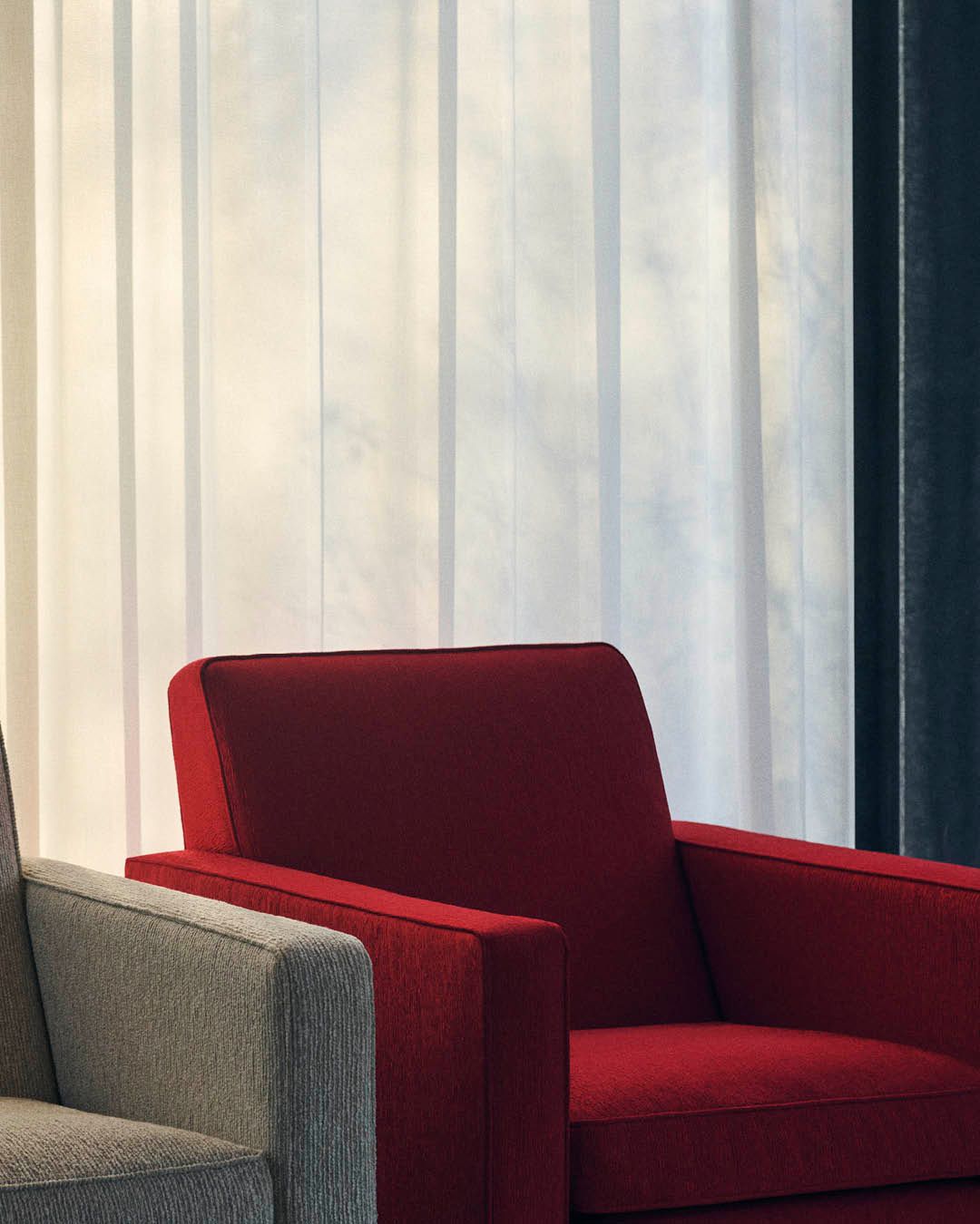 Two chairs in upholstery one in bright red and one in muted tone 