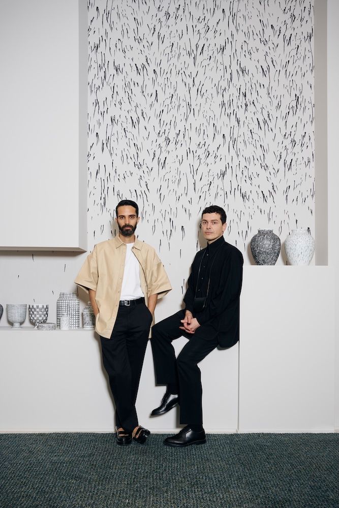 Formafantasma posing in front of patterned wallpaper 