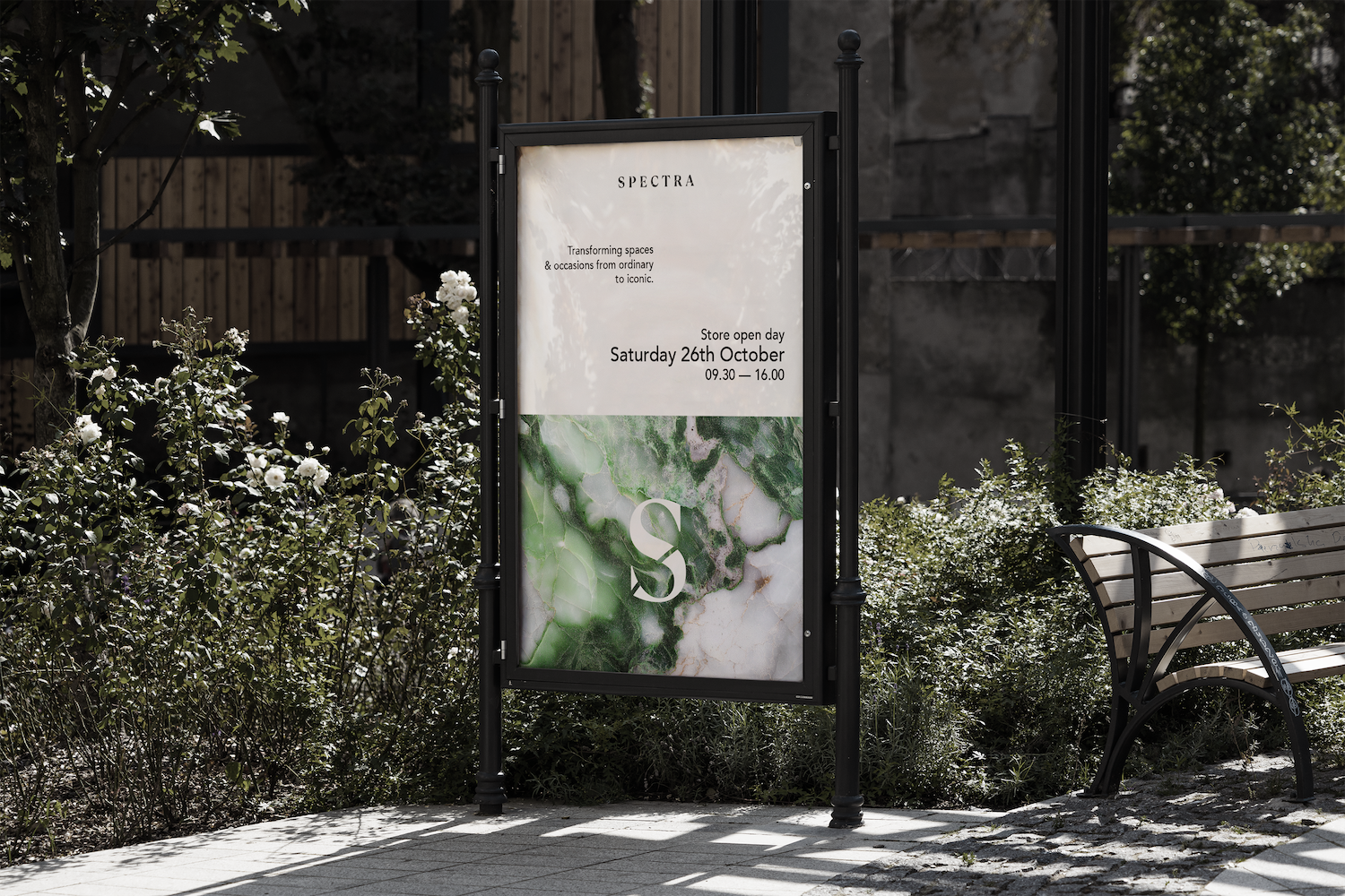 Advertising board for an exhibition with foliage in the background and a bench on the right 