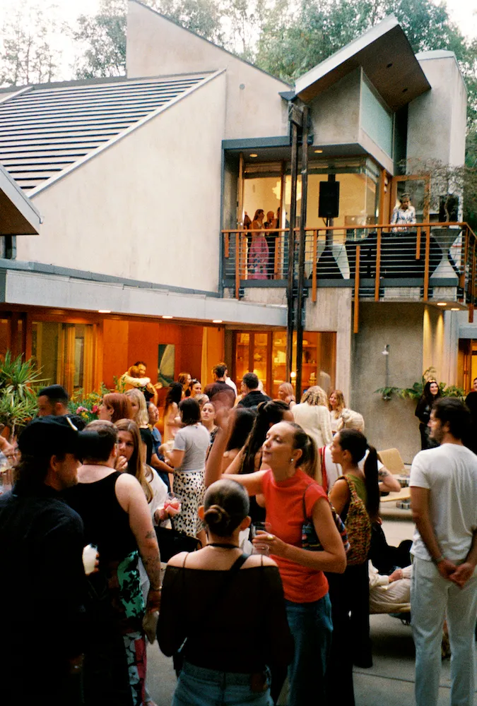 A crowd gathered outside a brutalist house 