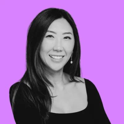 A smiling woman in black and white against a purple background.