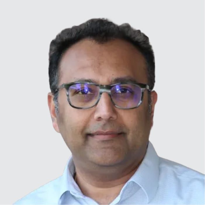 Headshot of a man with dark hair and patterned glasses, smiling slightly.