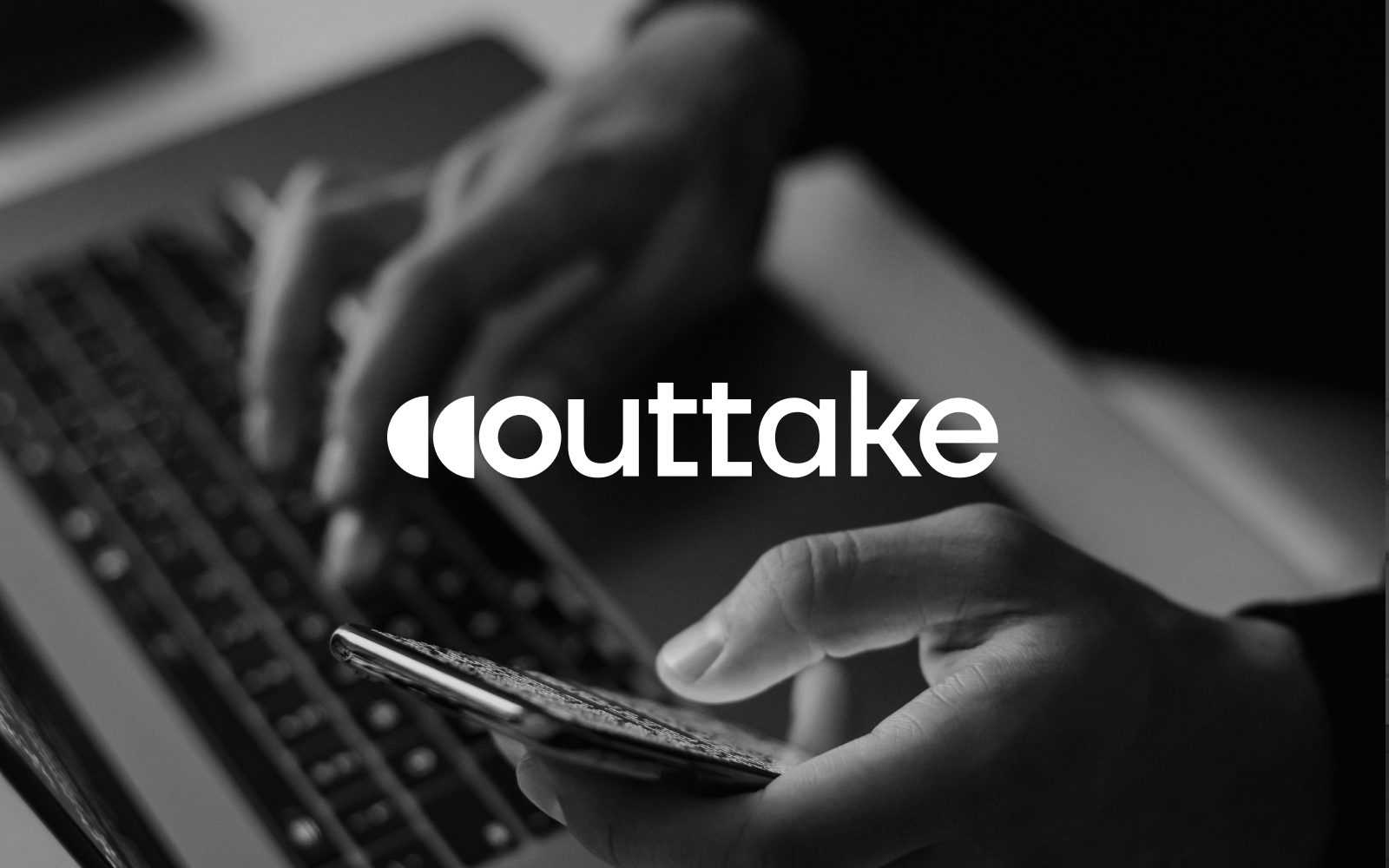 Outtake logo on a black and white image of hands using a laptop and smartphone.