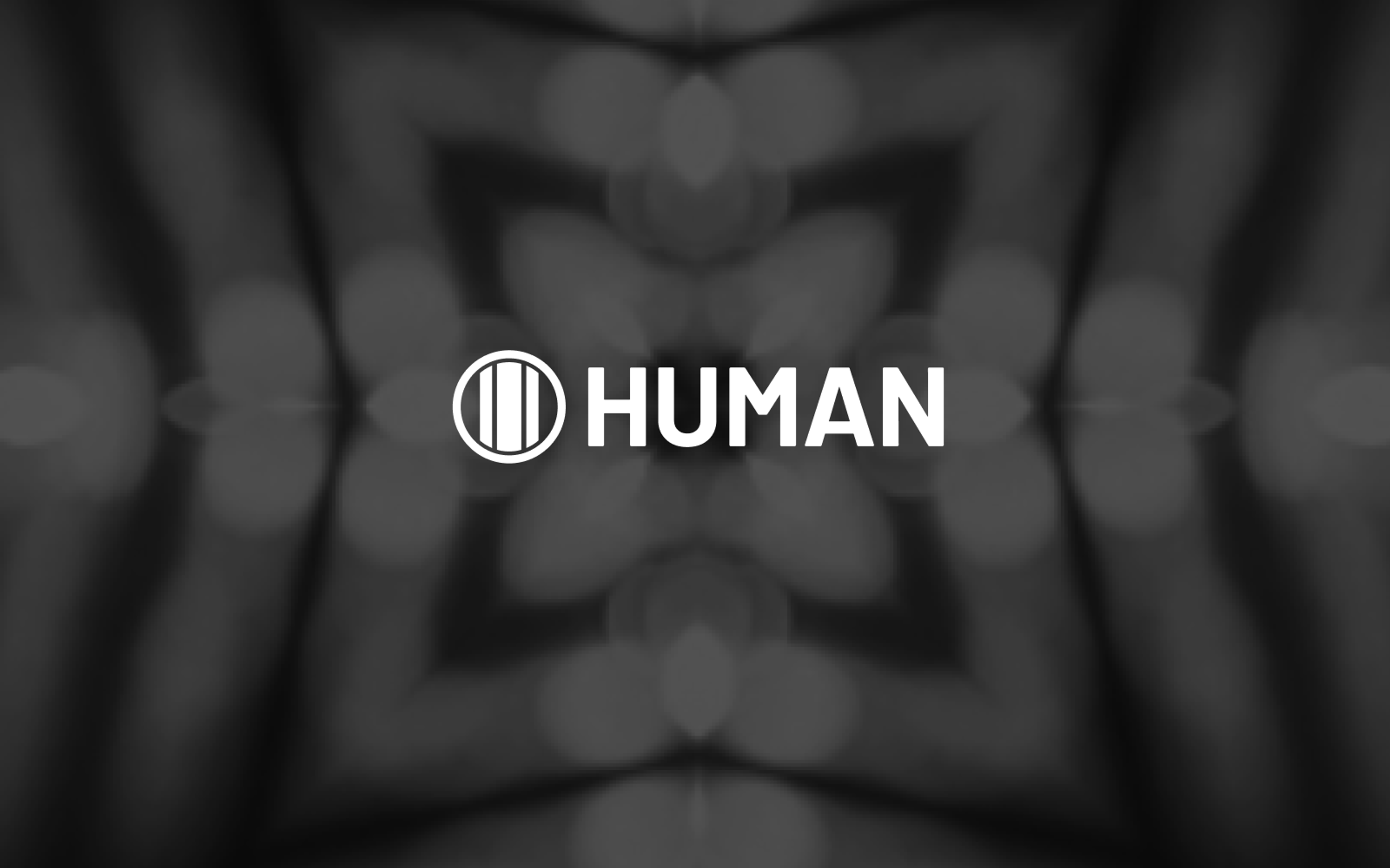 White 'HUMAN' text and logo (a circle with three vertical lines) on a dark, blurred, symmetrical background with bokeh lights.