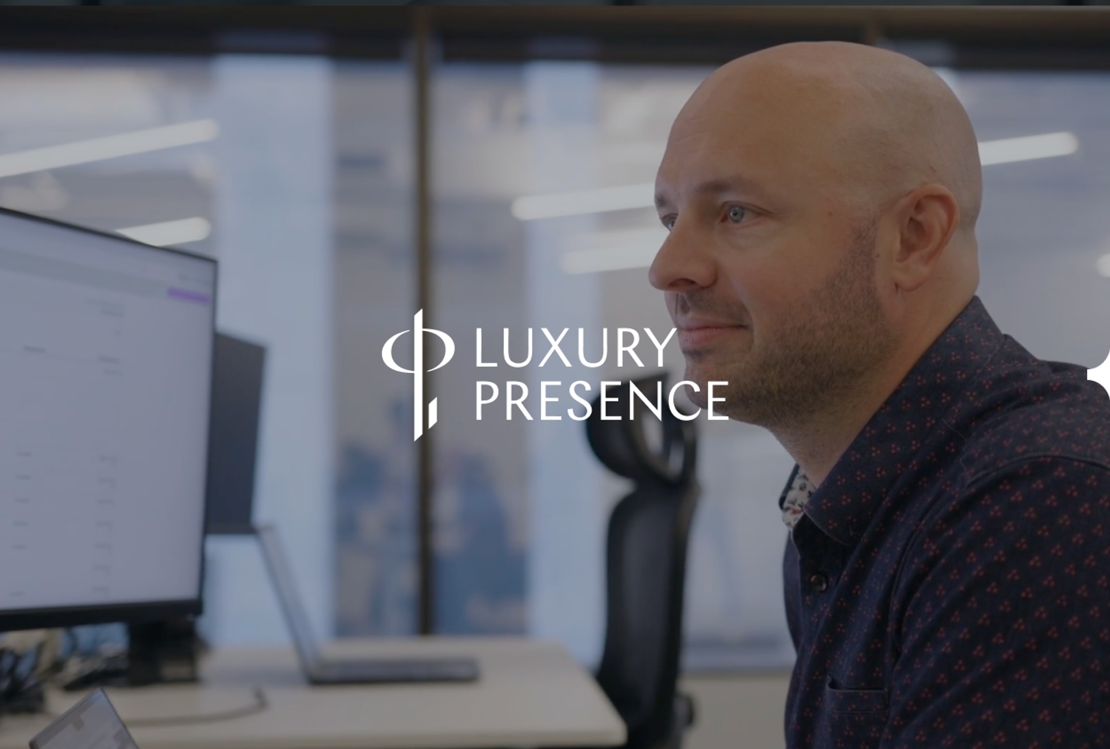 A man with a beard and shaved head in an office, with the 'Luxury Presence' logo overlaid.