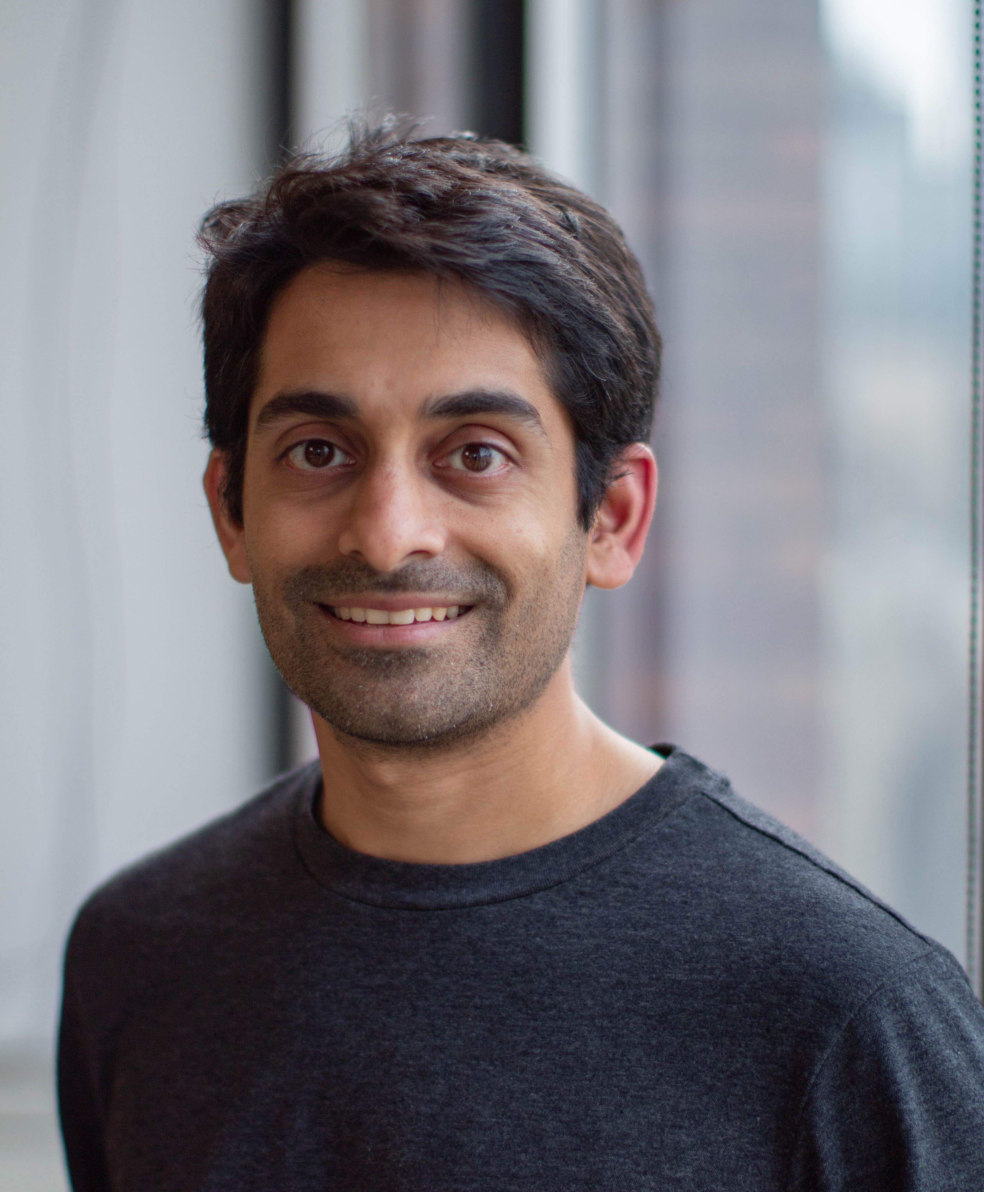 a man in a grey shirt is smiling for the camera
