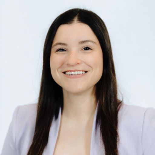 Smiling woman with long dark hair in a light purple blazer.