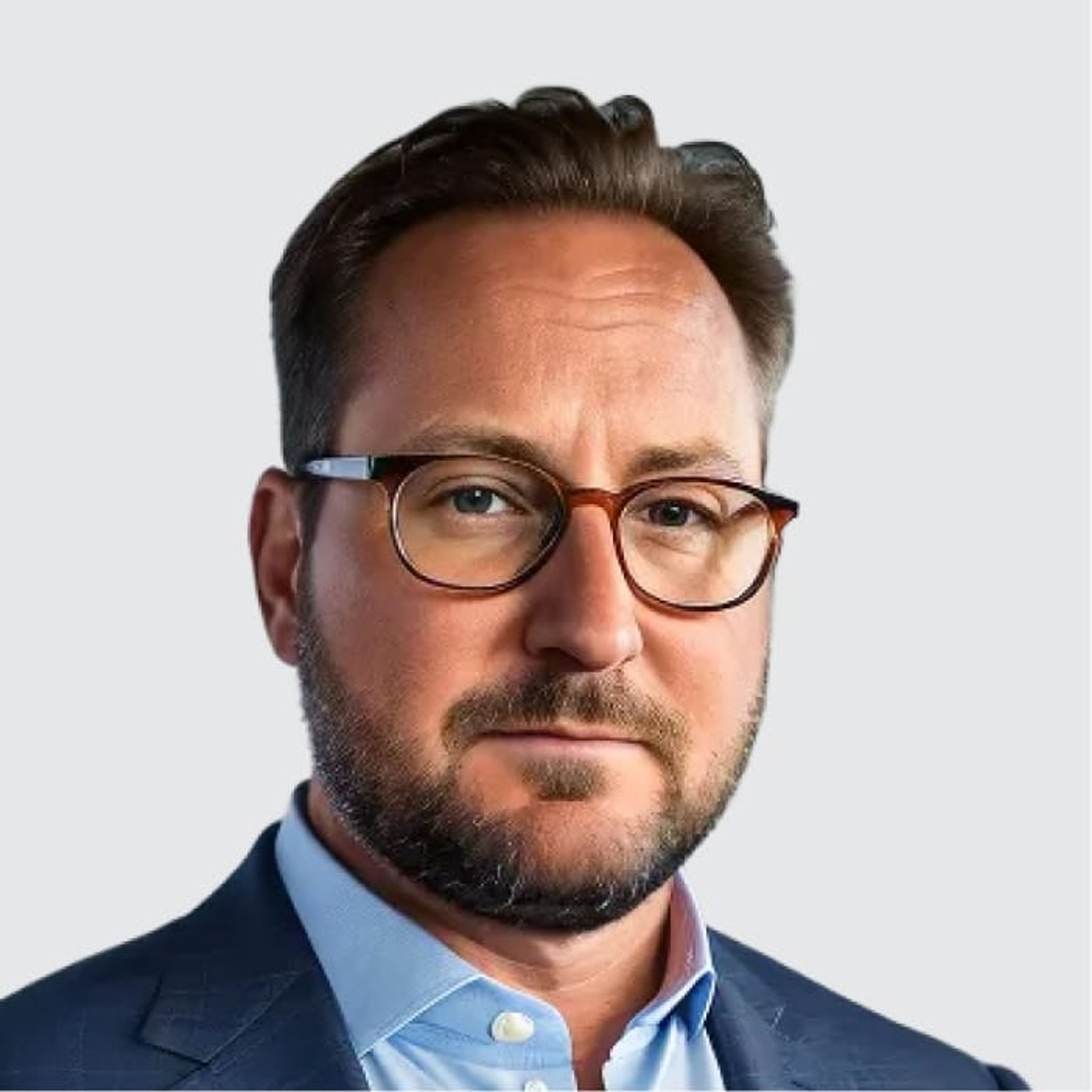 Headshot of a man with brown hair, a beard, and glasses, wearing a blue shirt and dark suit jacket.