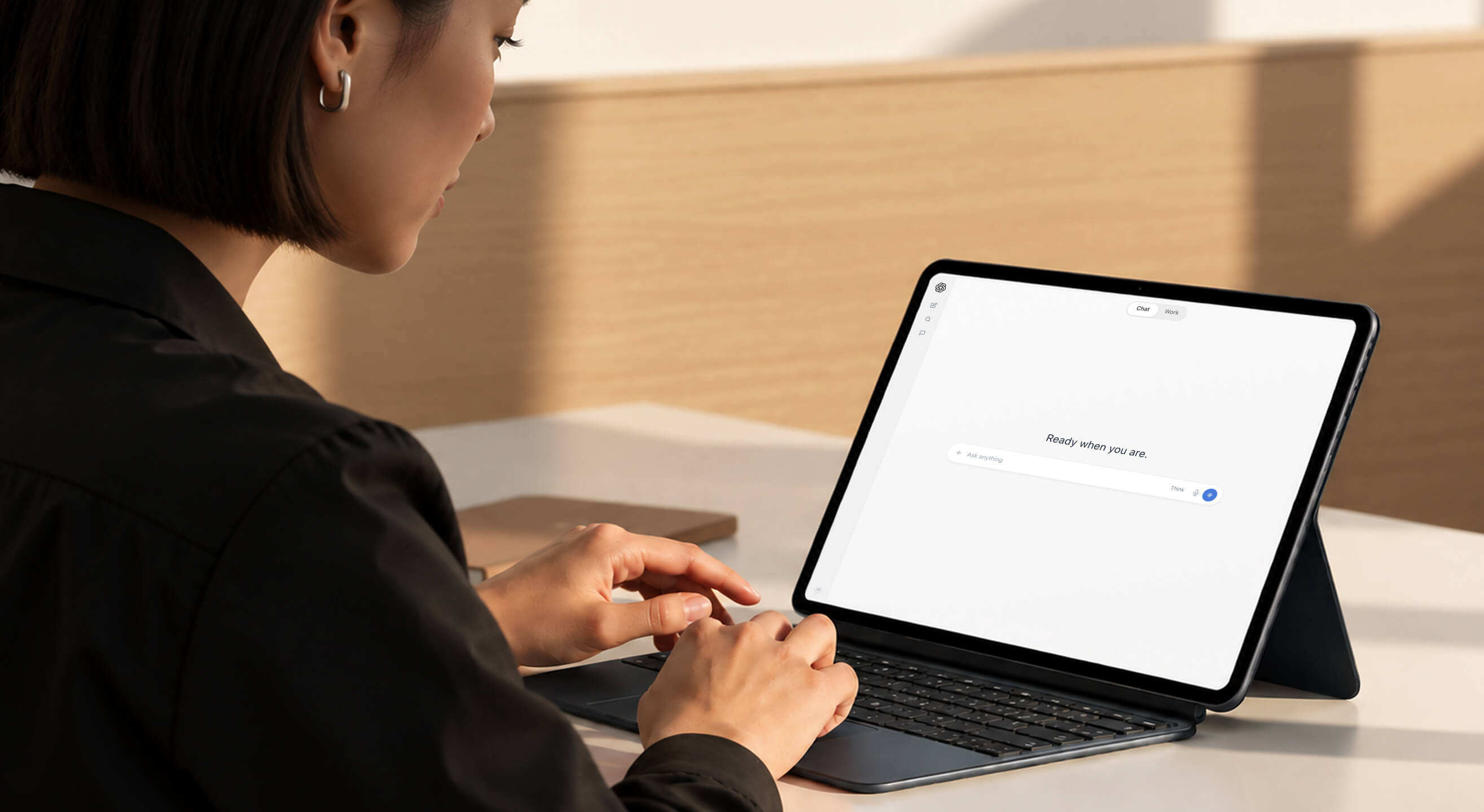 A person types on a tablet with a keyboard case, the screen displaying "Ready when you are".