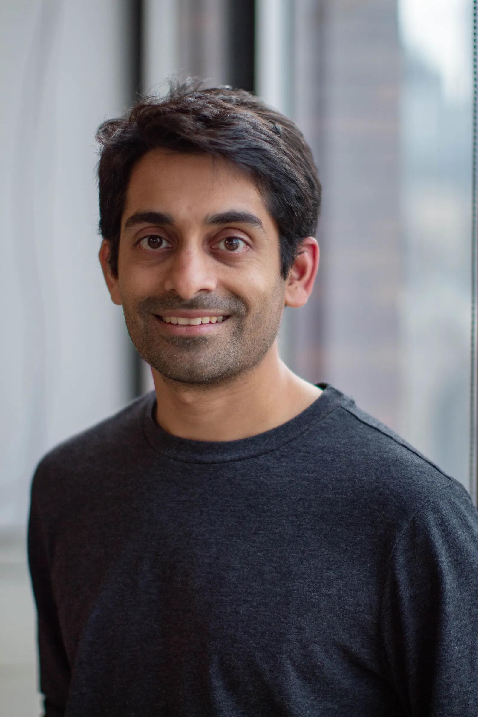 a man in a grey shirt is smiling for the camera