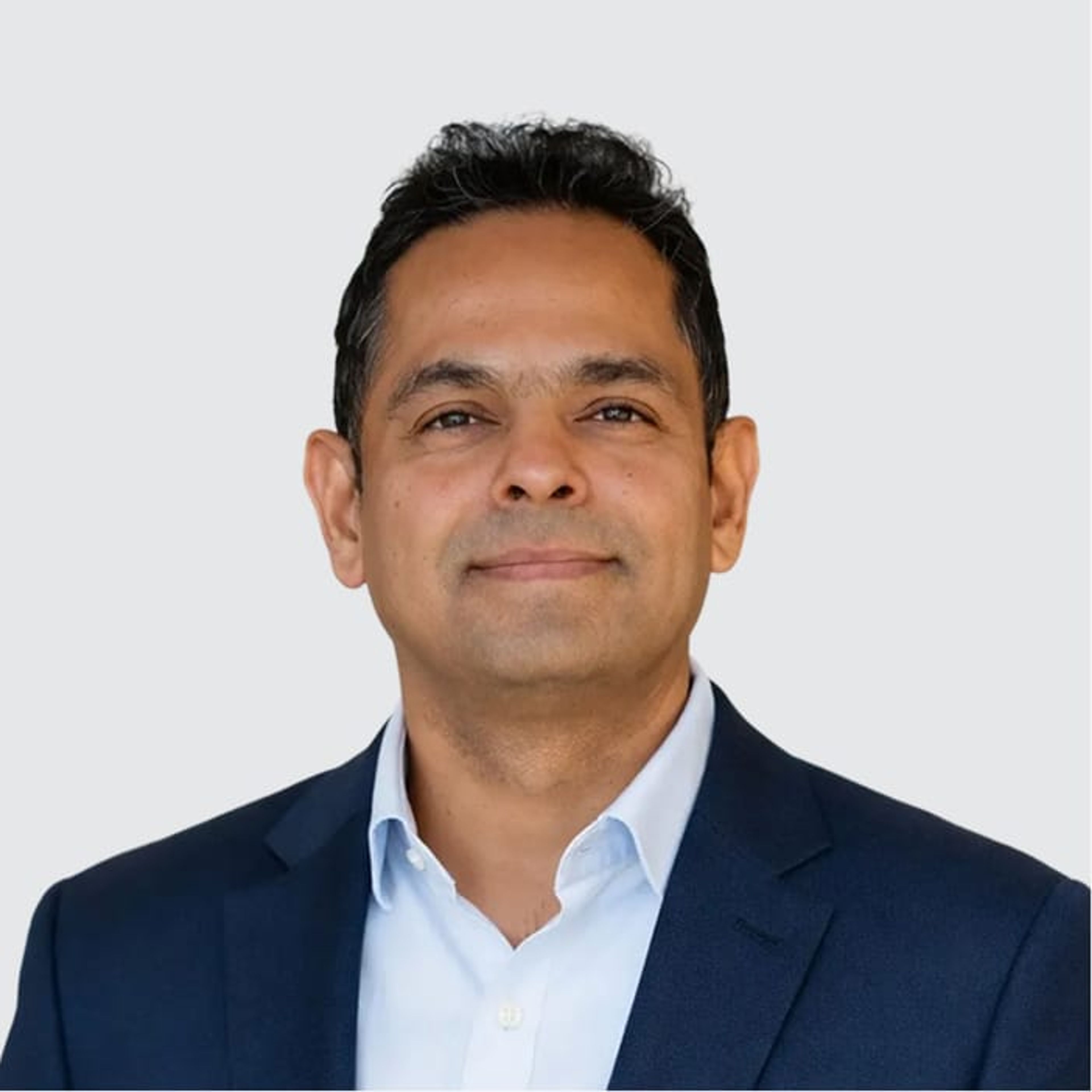 Headshot of a smiling man in a blue suit jacket and light blue shirt.