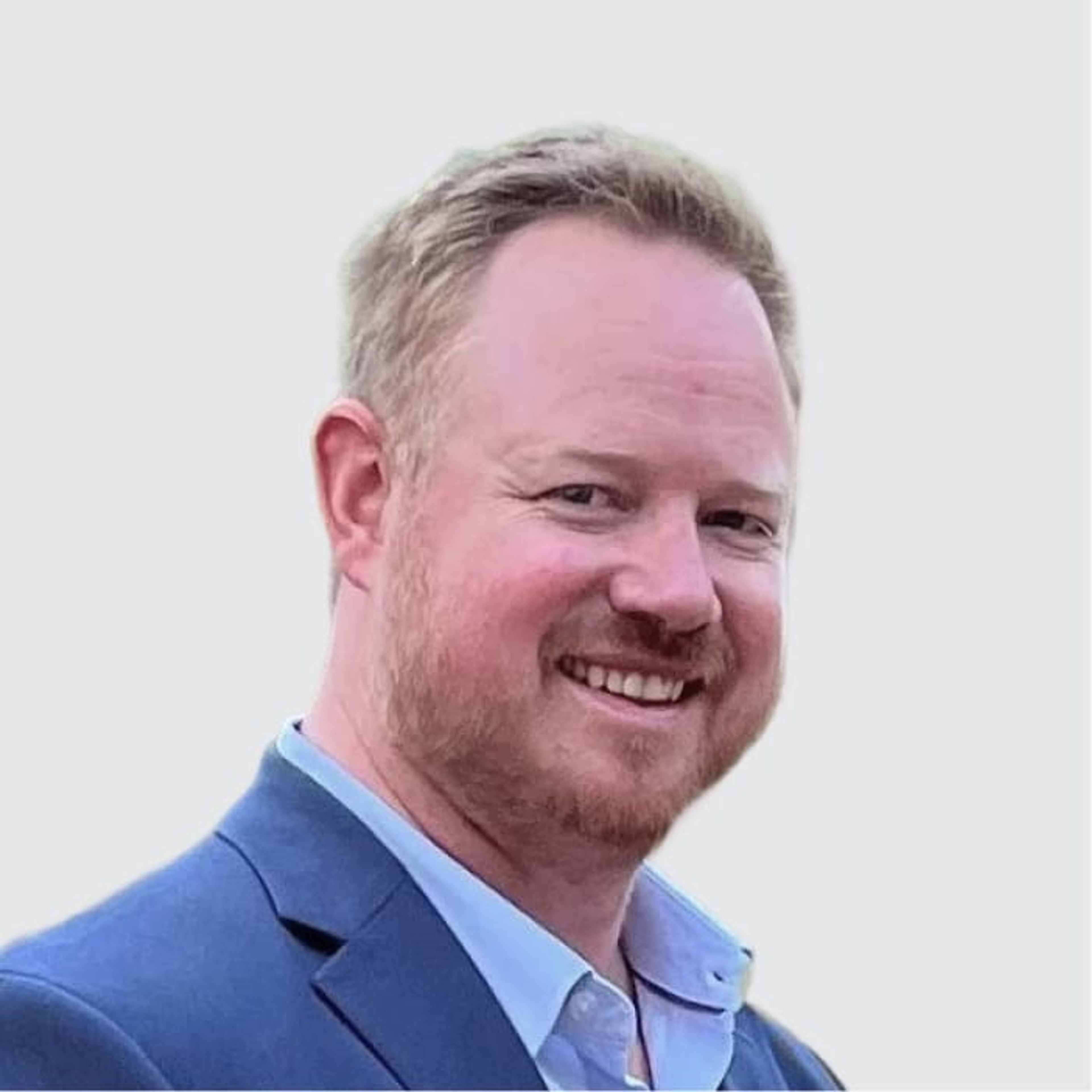 Smiling man with reddish-blonde hair and beard wearing a blue suit jacket.