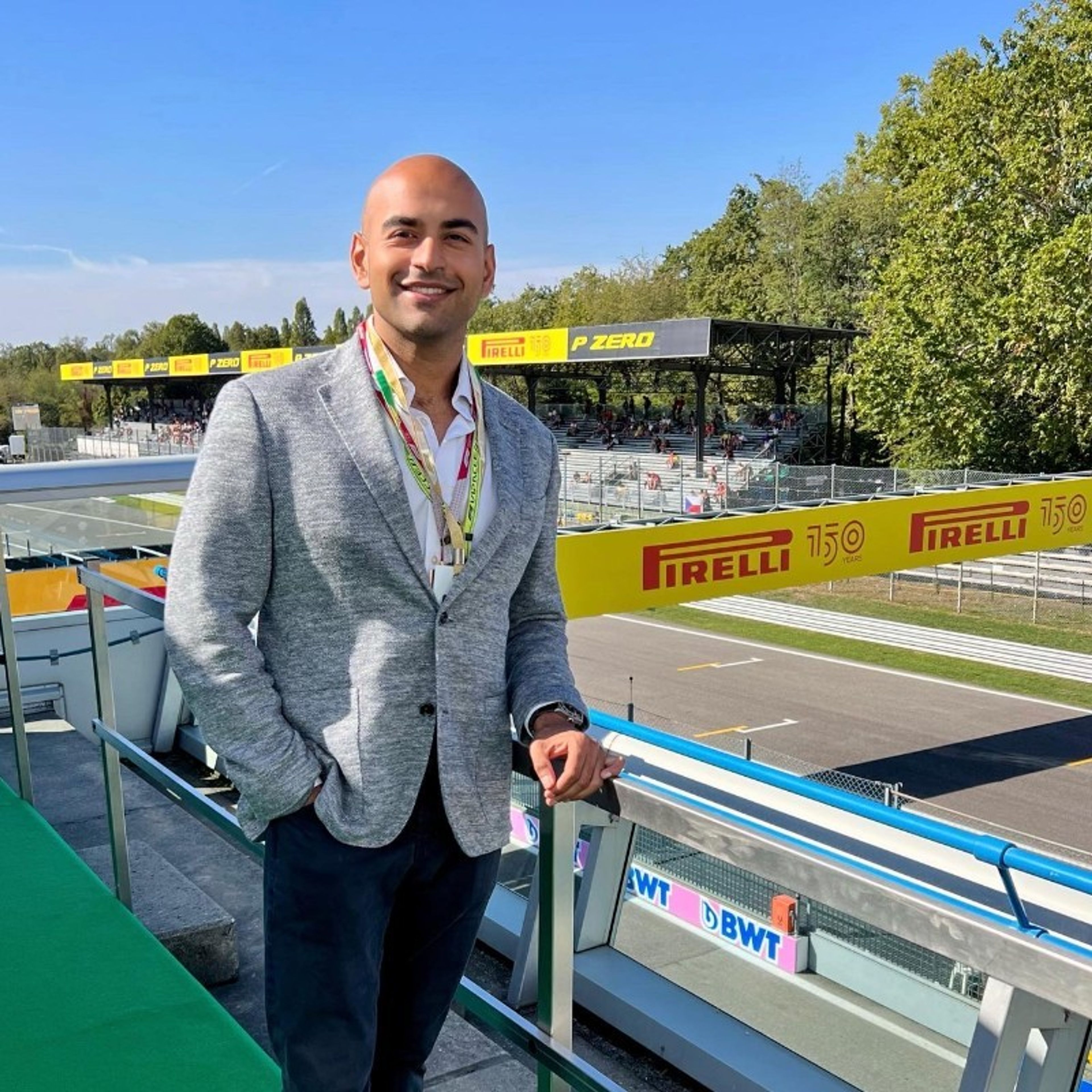 a man in a suit is standing on a balcony overlooking a race track .