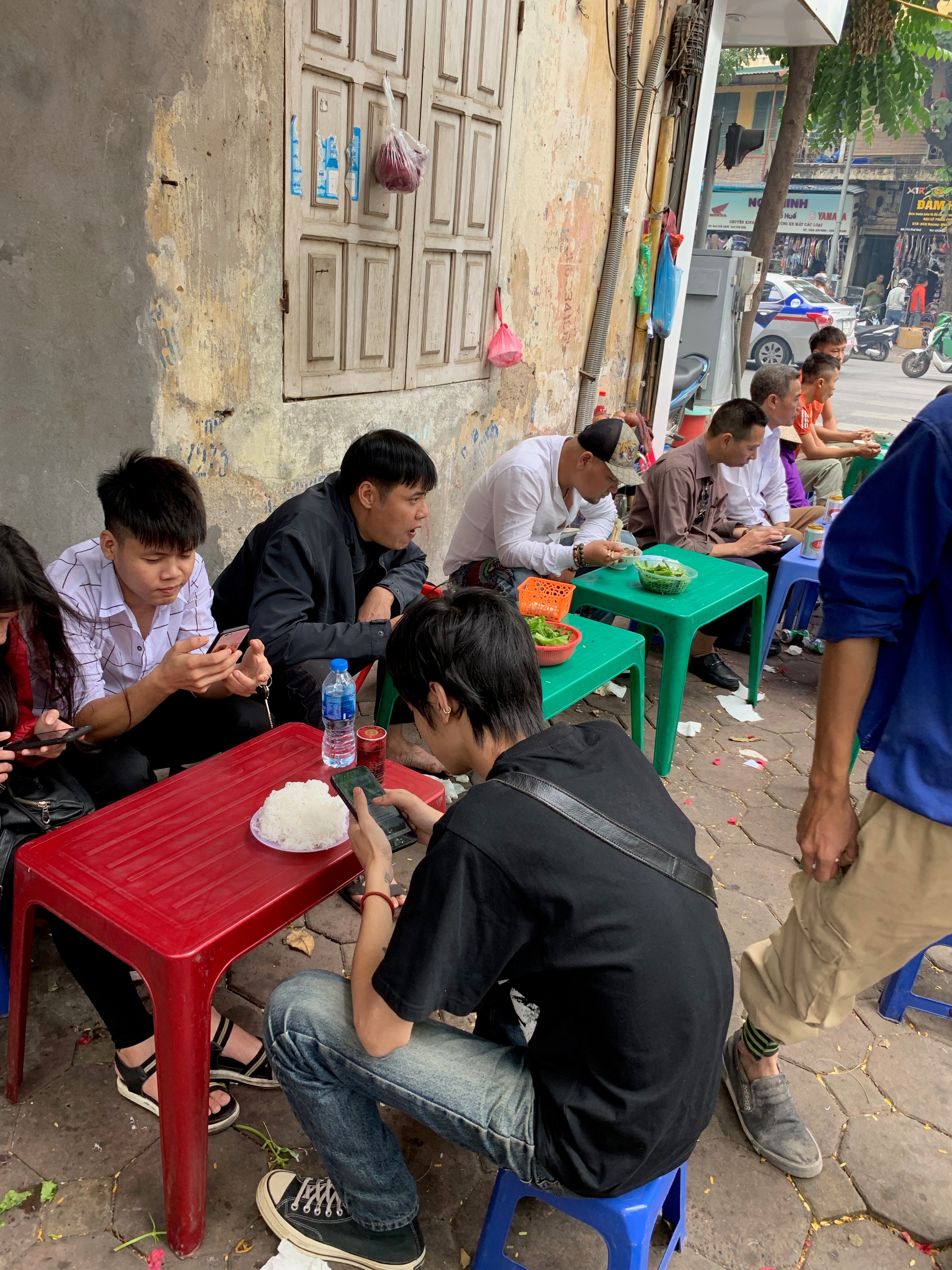 People eat at low tables outside a neighborhood restaurant.
