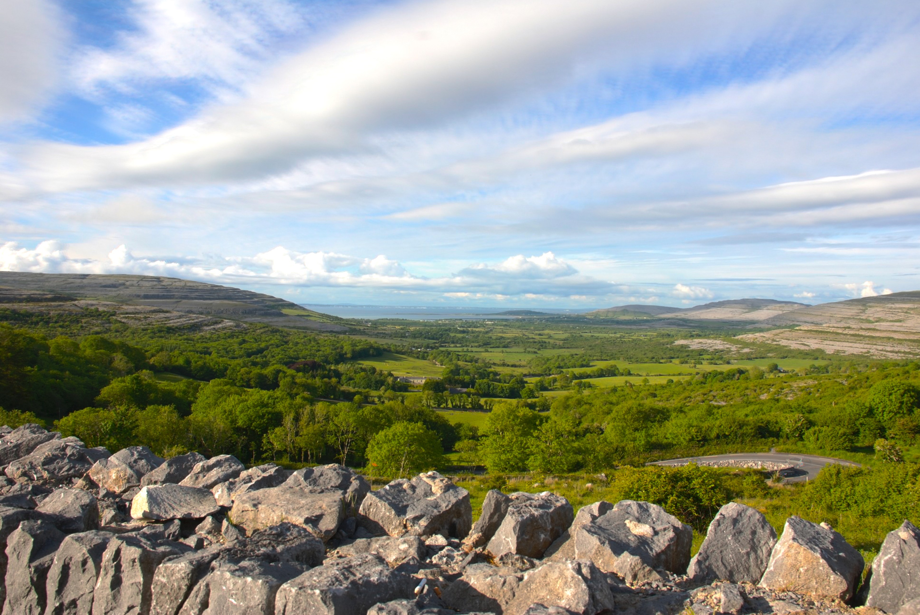 A rocky hillside and green valley seen from a road viewpoint.