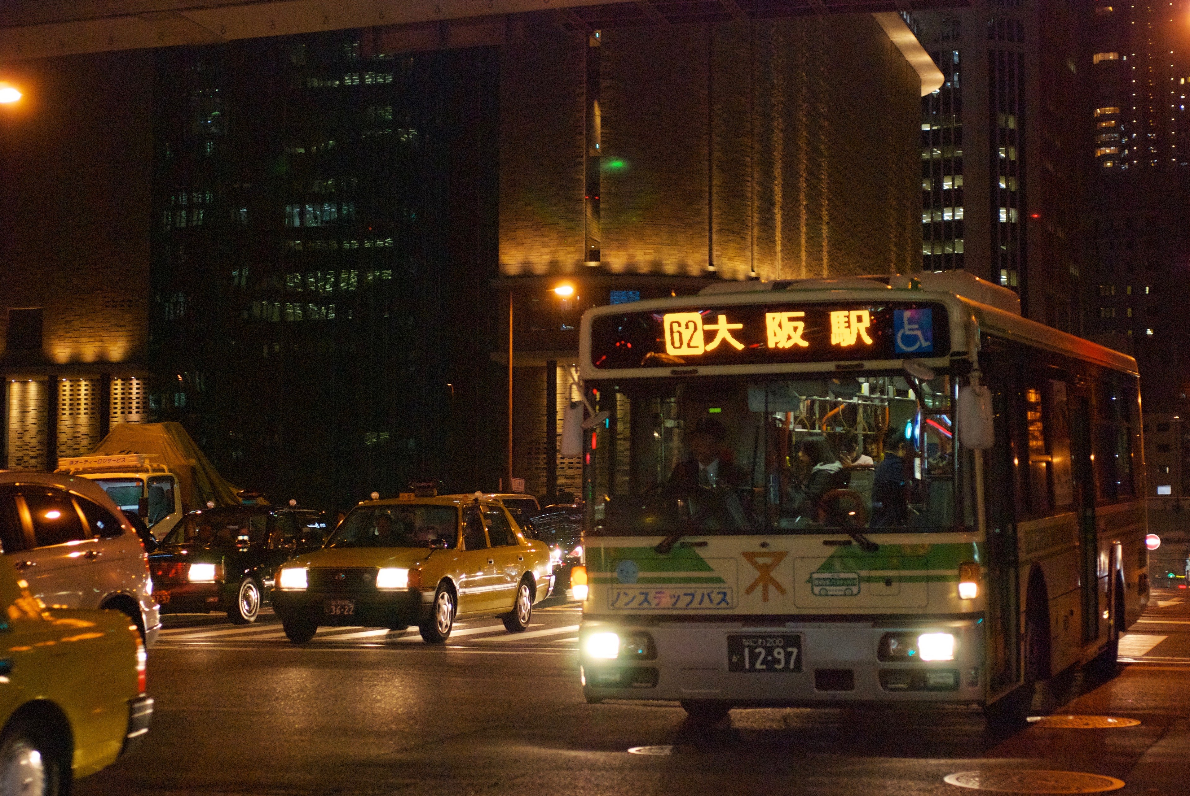 A city bus passes along a busy street at night.