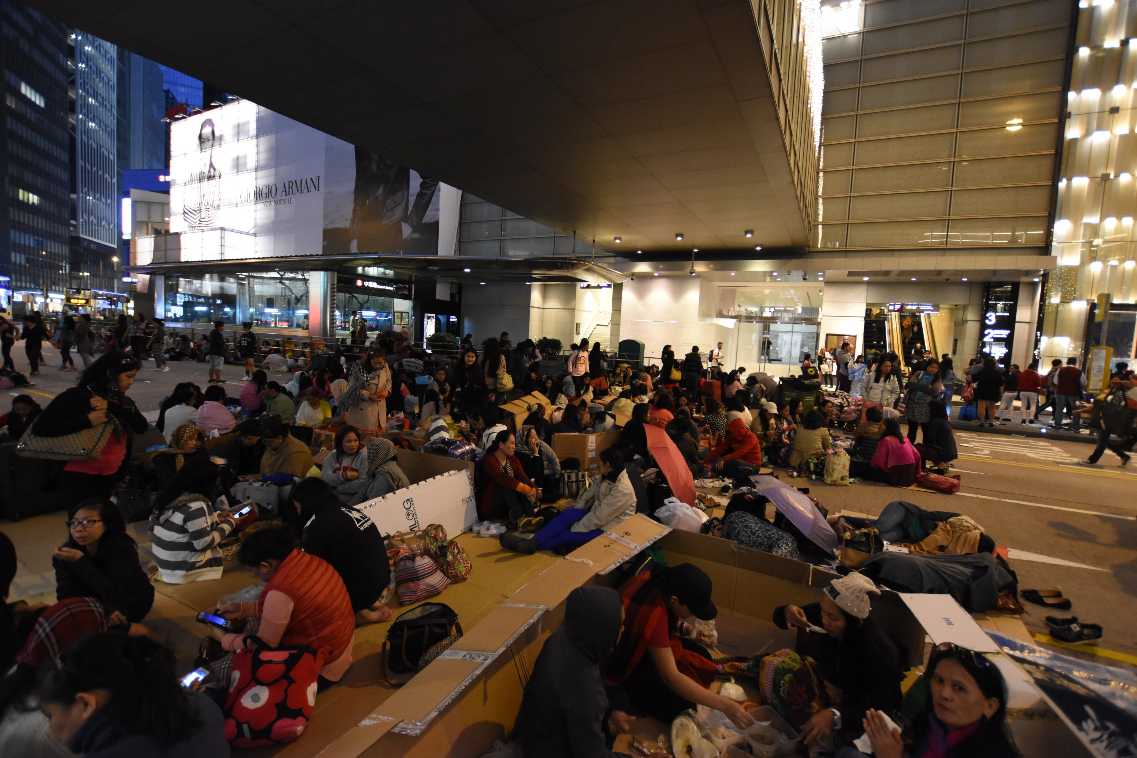 Travelers sit in rows of chairs inside a large transit hall.