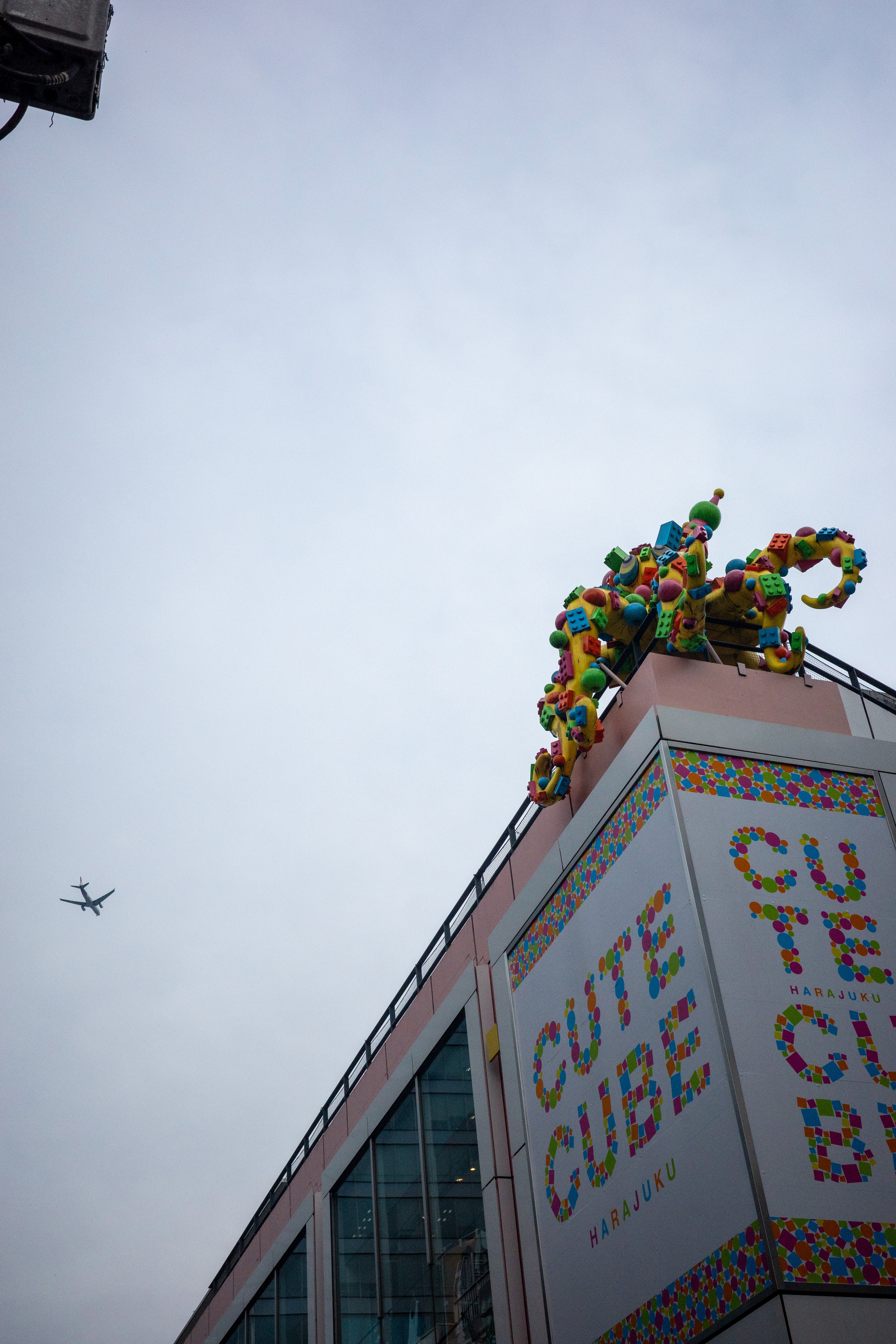 Colorful rooftop figures sit above a building sign.