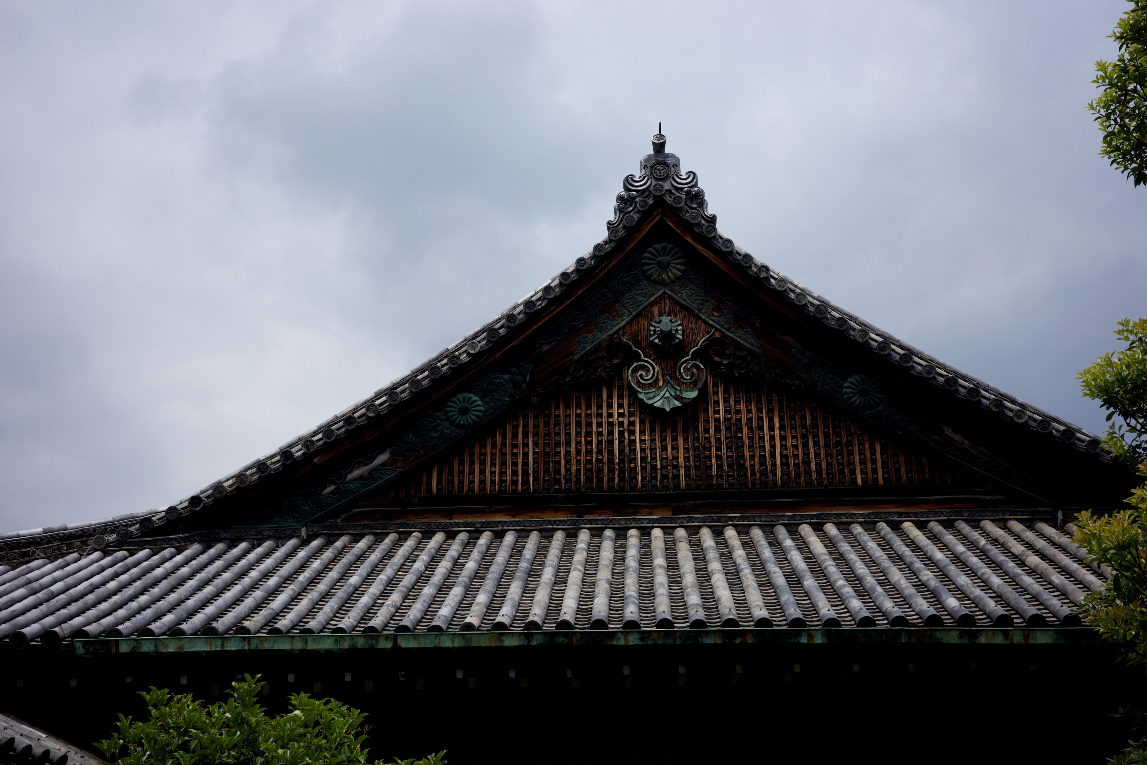 An ornate temple roof stands against a cloudy sky.