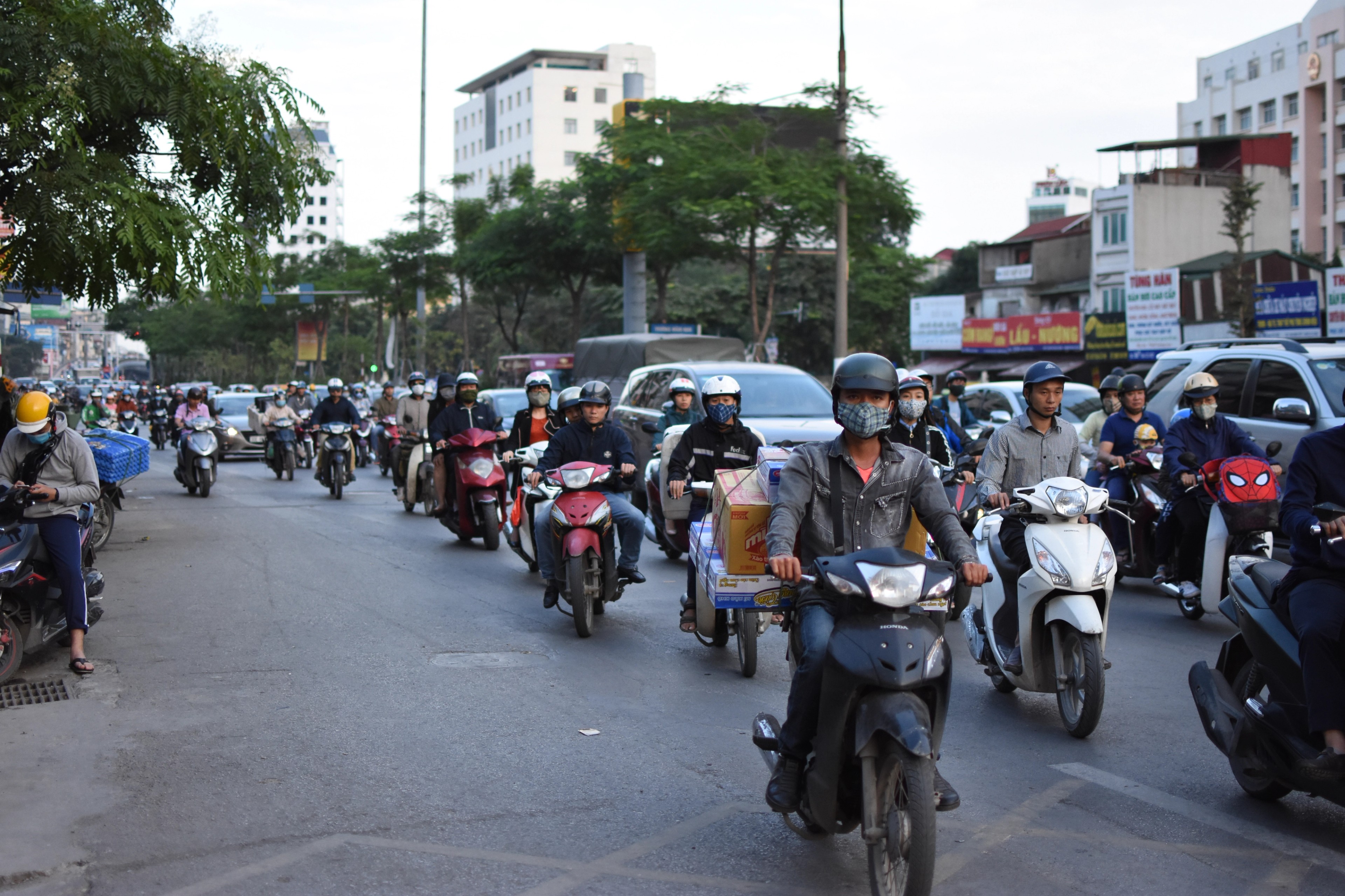 Motorcycles crowd a busy intersection between modern buildings.