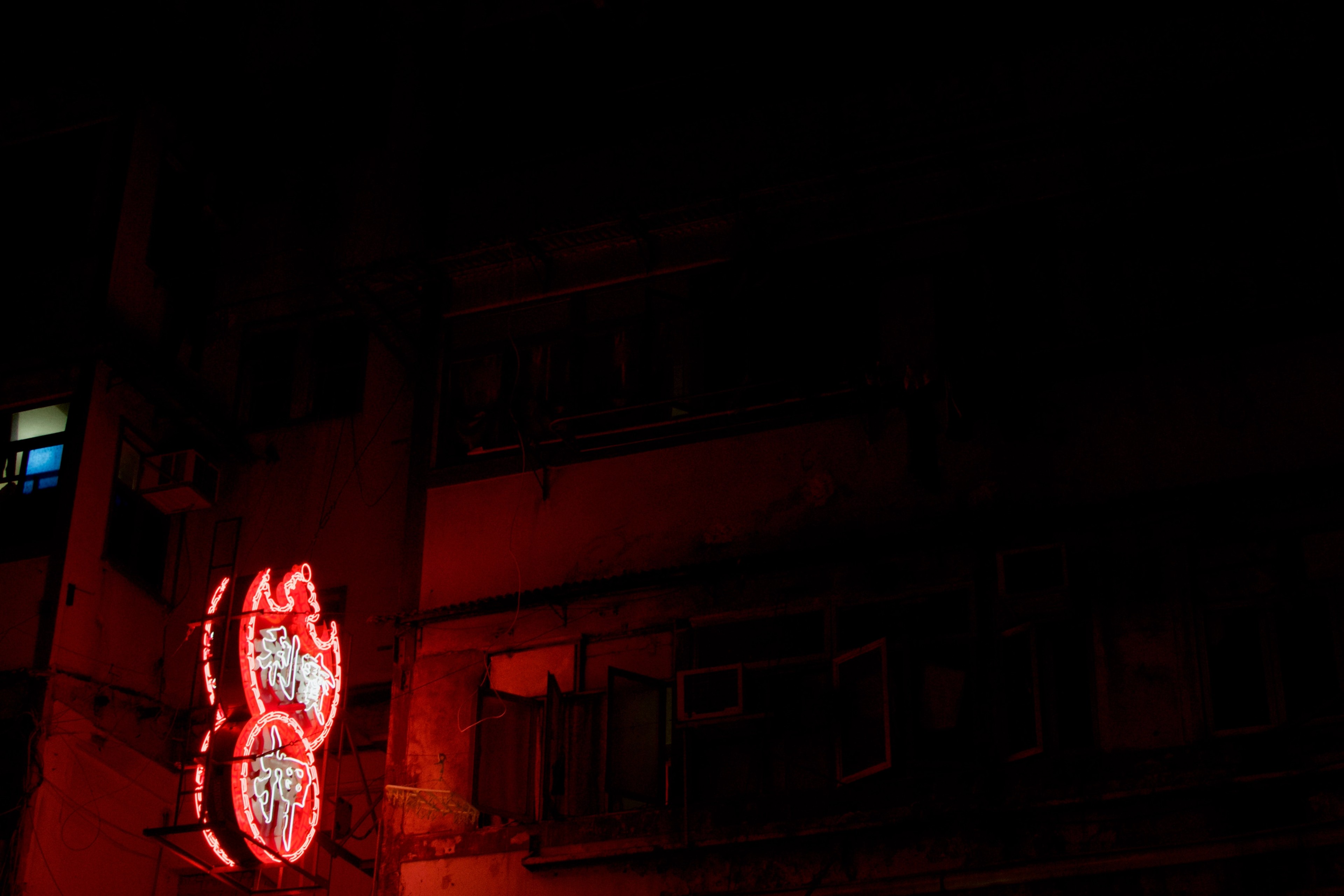 Red neon characters glow on a mostly dark building façade.