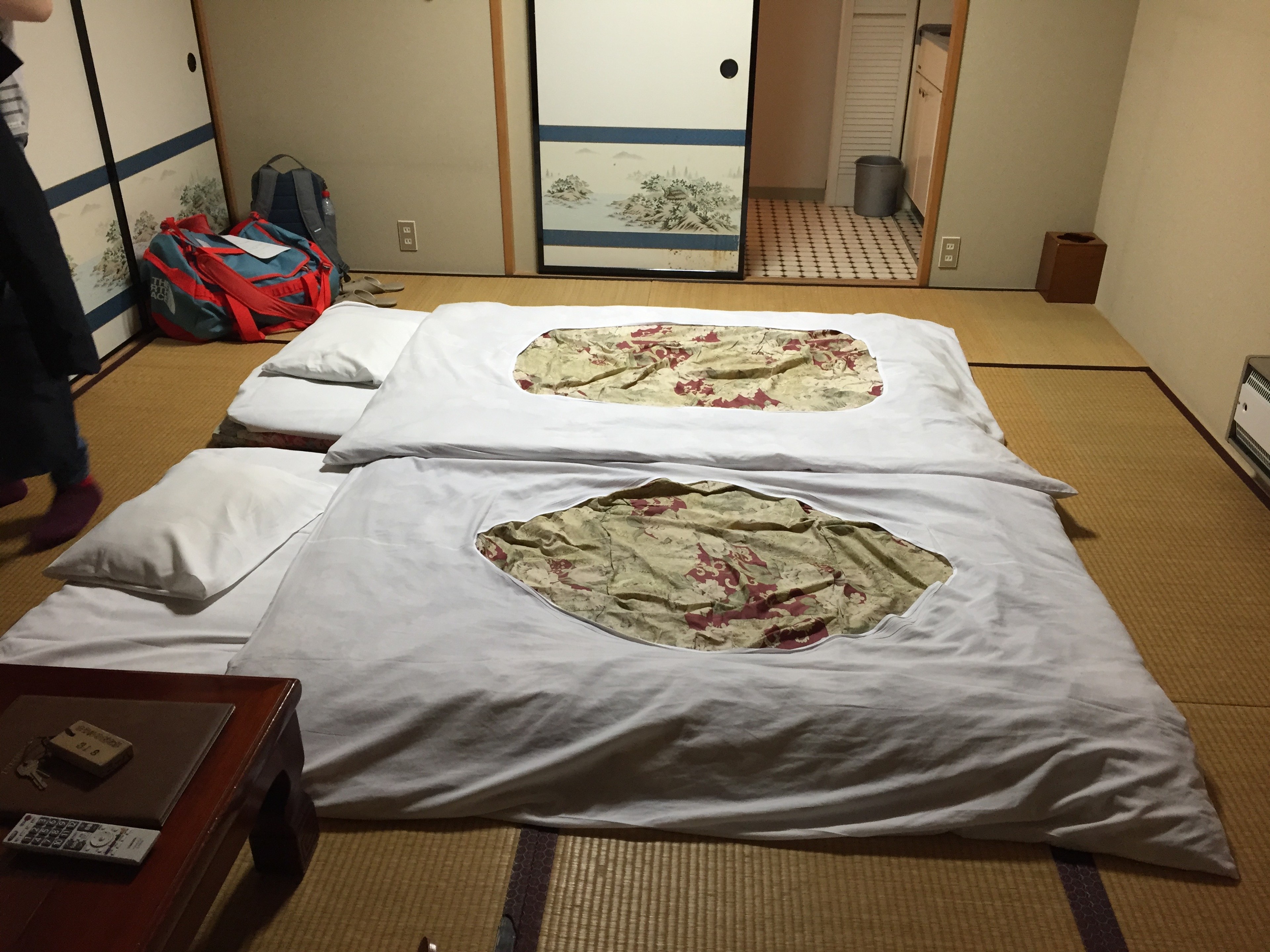 A futon and folded bedding lie on the floor of a tatami room.