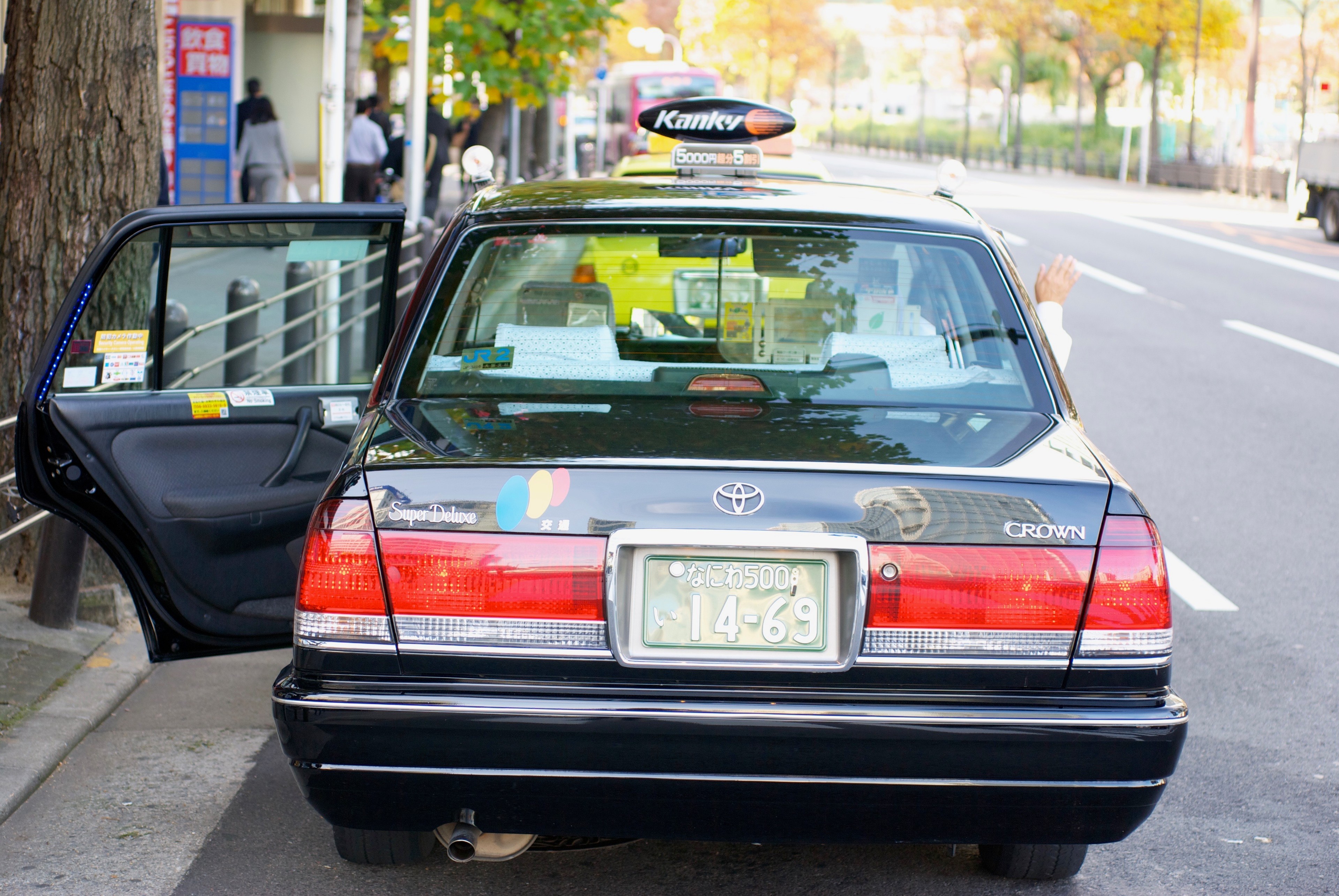 A taxi is parked at the curb with its rear passenger door open.