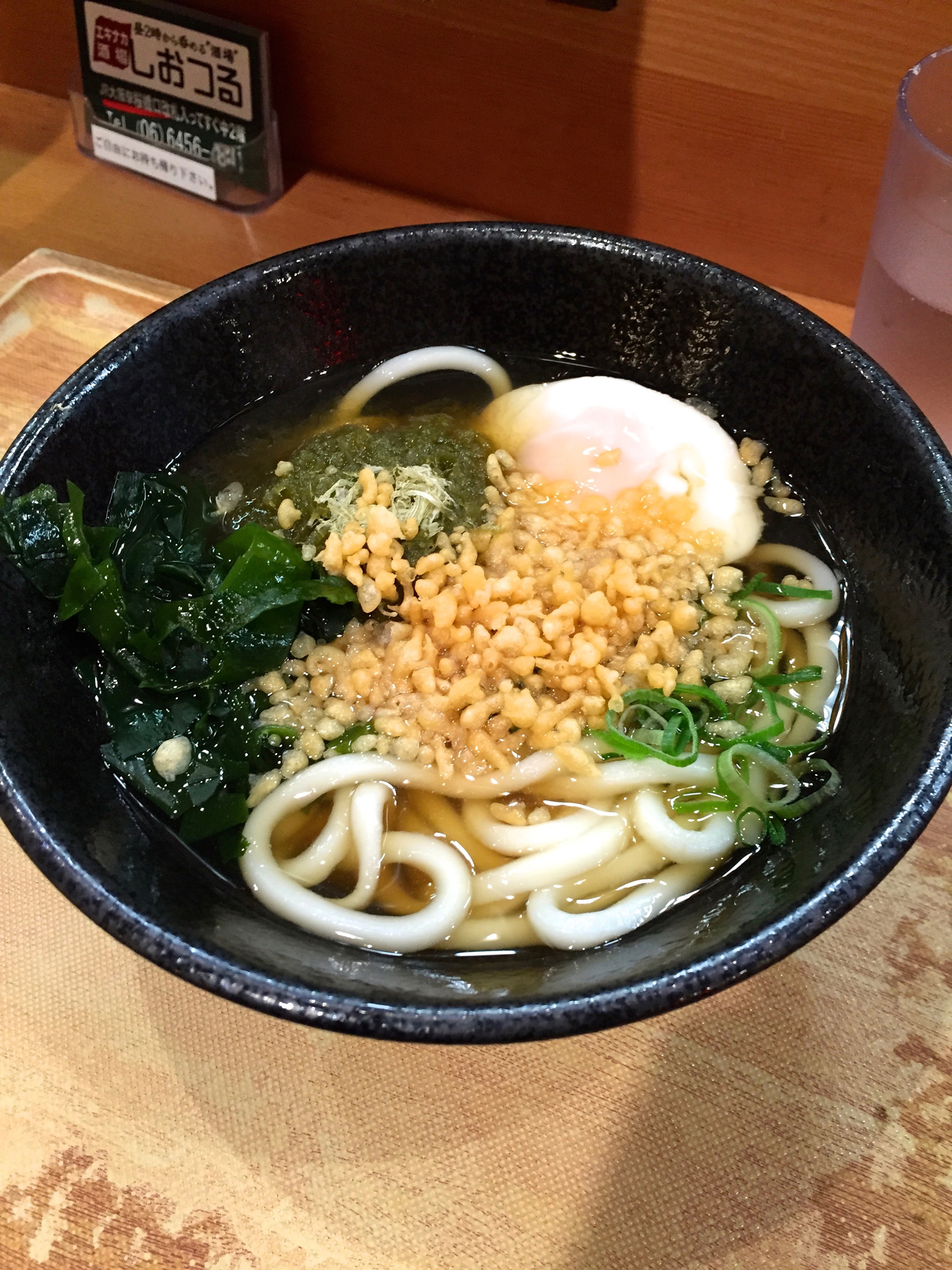 A bowl of udon noodle soup sits on a counter.
