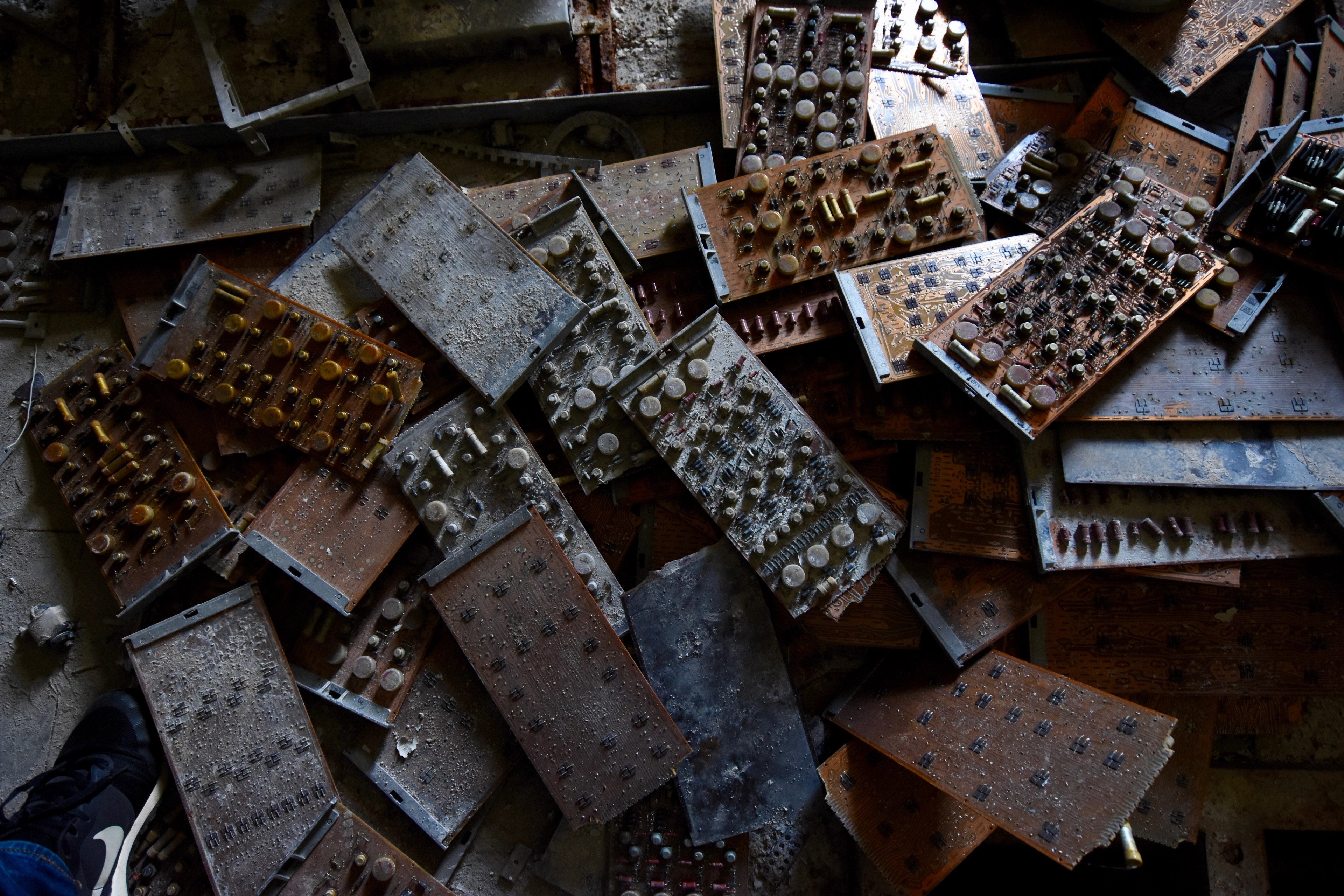 Rows of rusted electrical panels lie scattered on the floor.