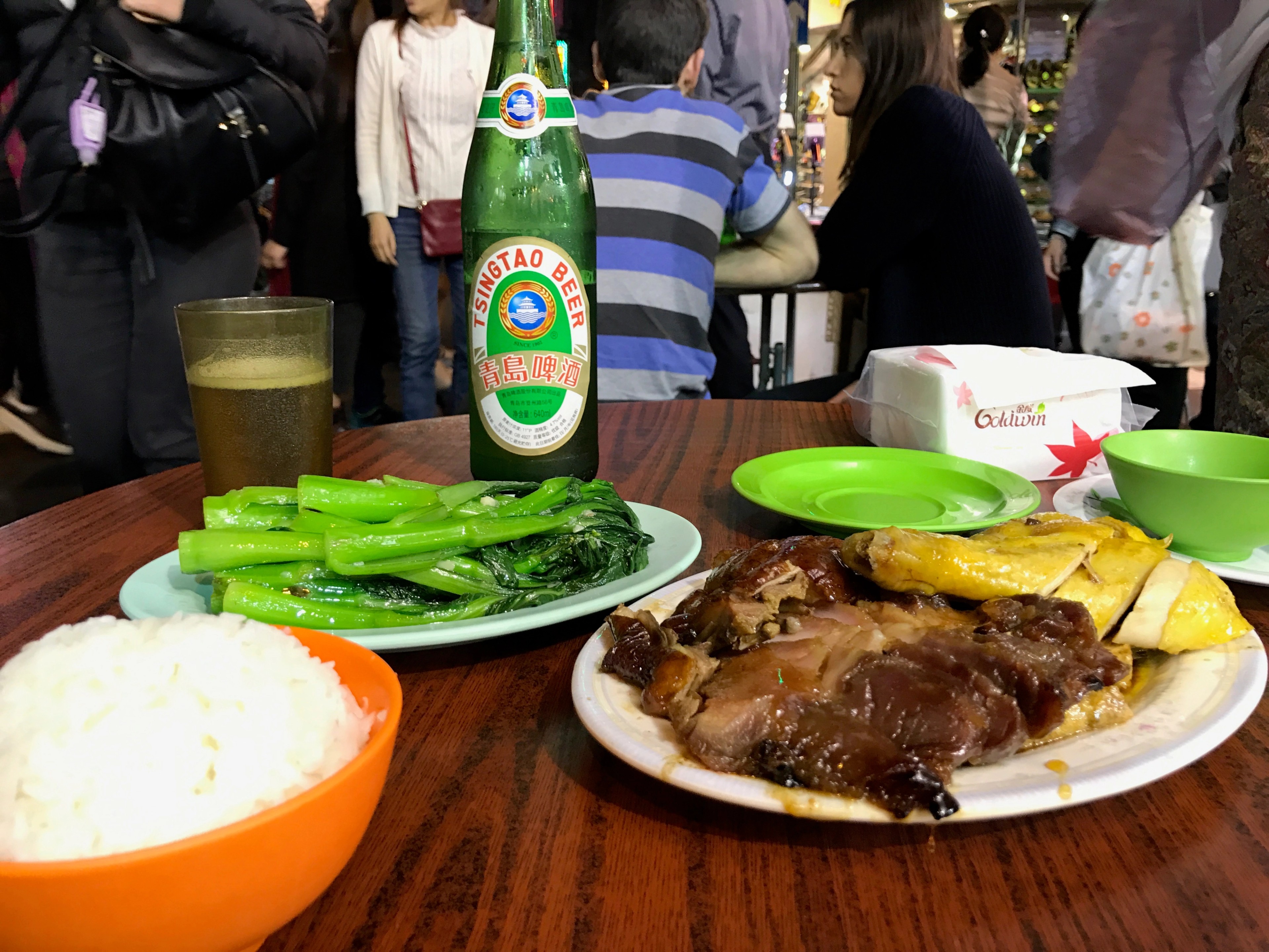 A plate of rice, meat, and green vegetables is served with chopsticks.
