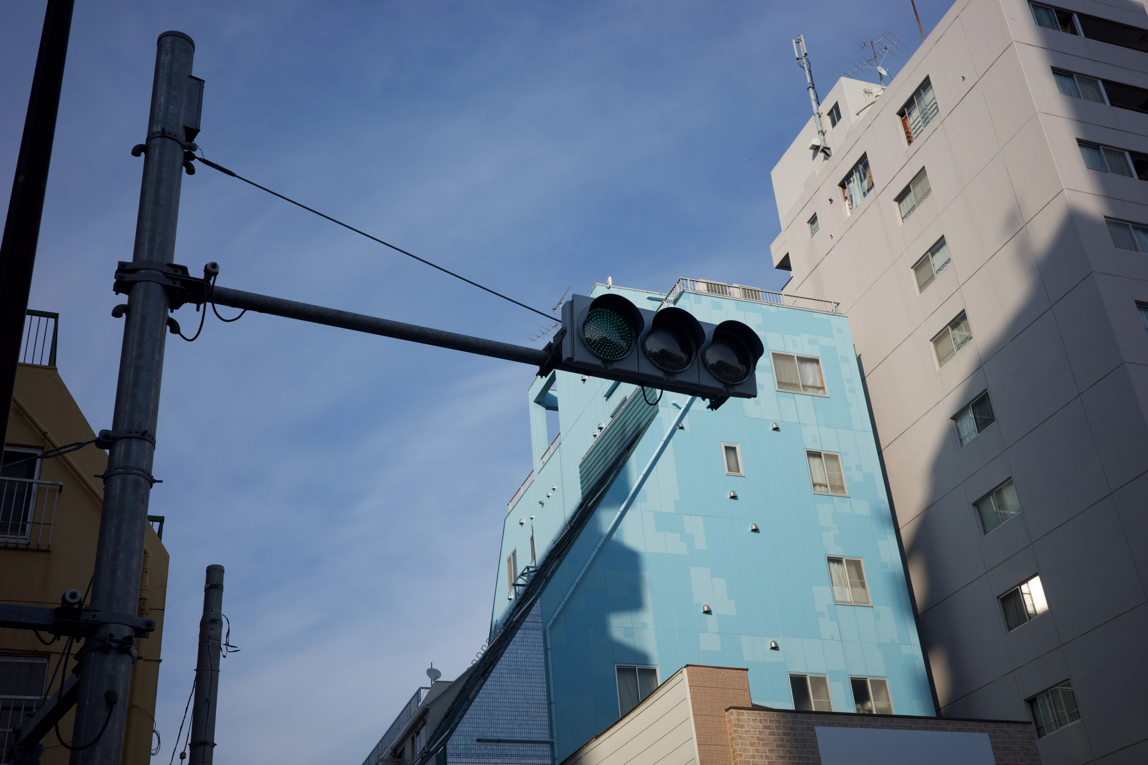 A pale blue apartment facade rises above the street.