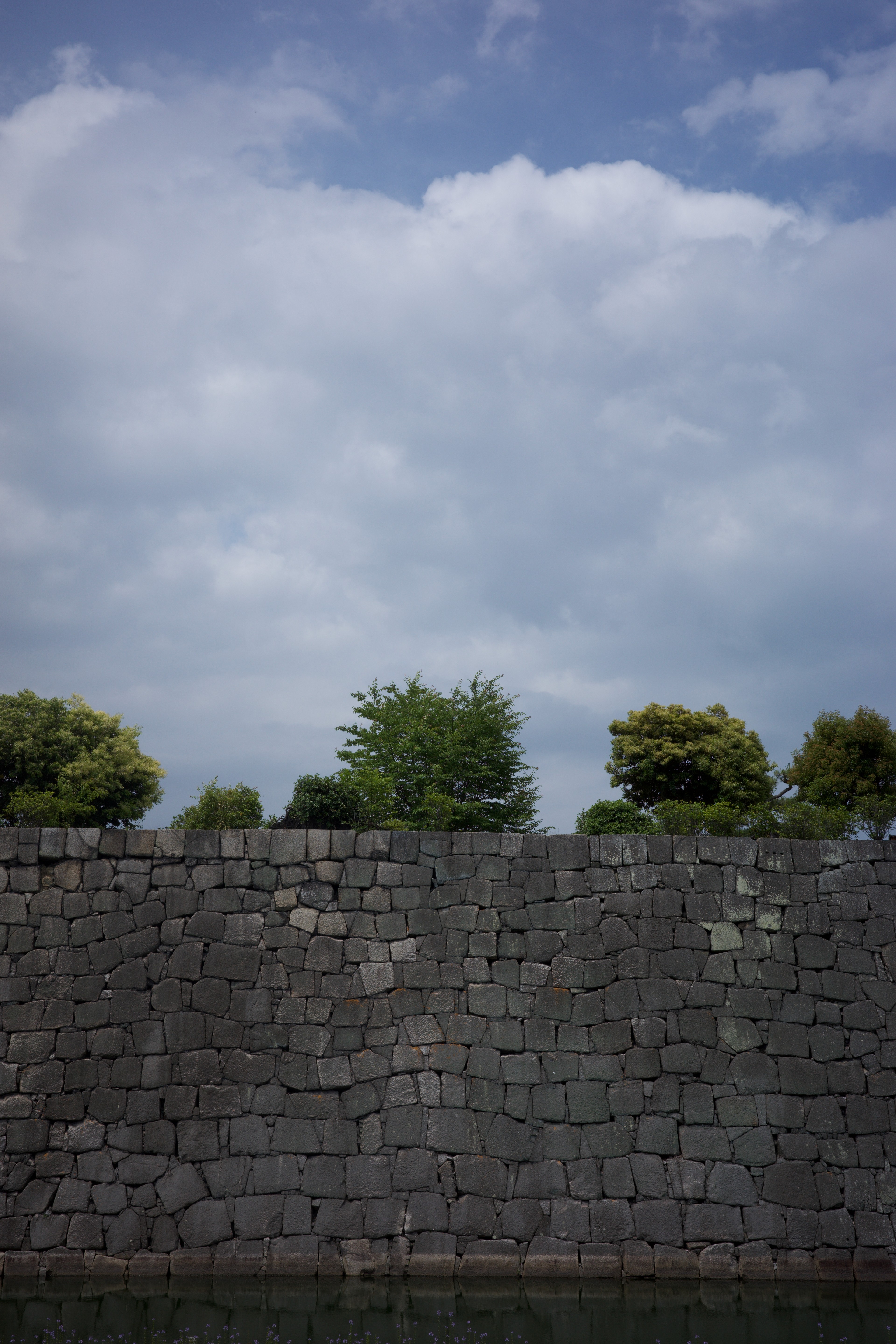A cloudy sky rises above a long stone wall.
