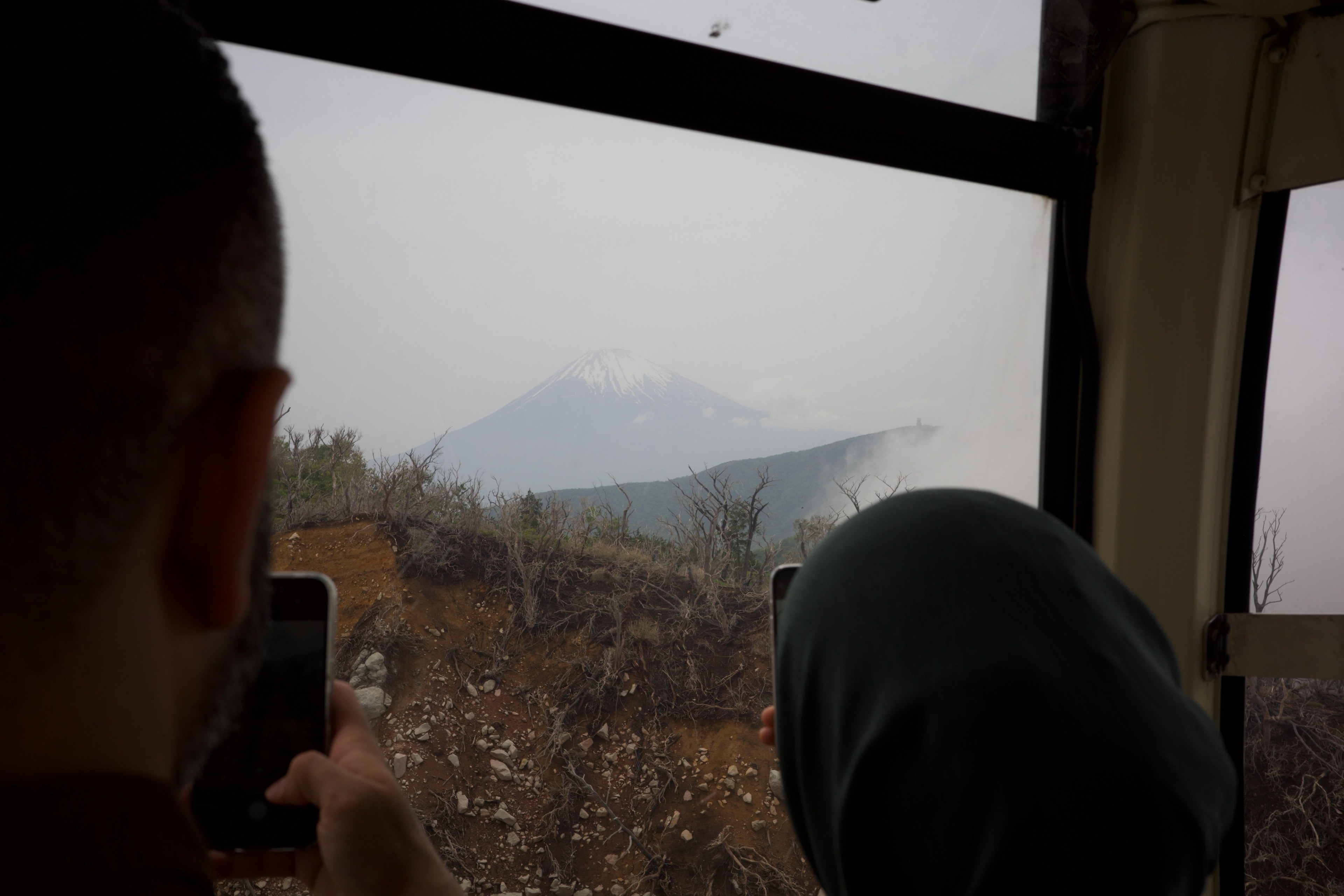 Passengers look toward mountain scenery from a gondola.