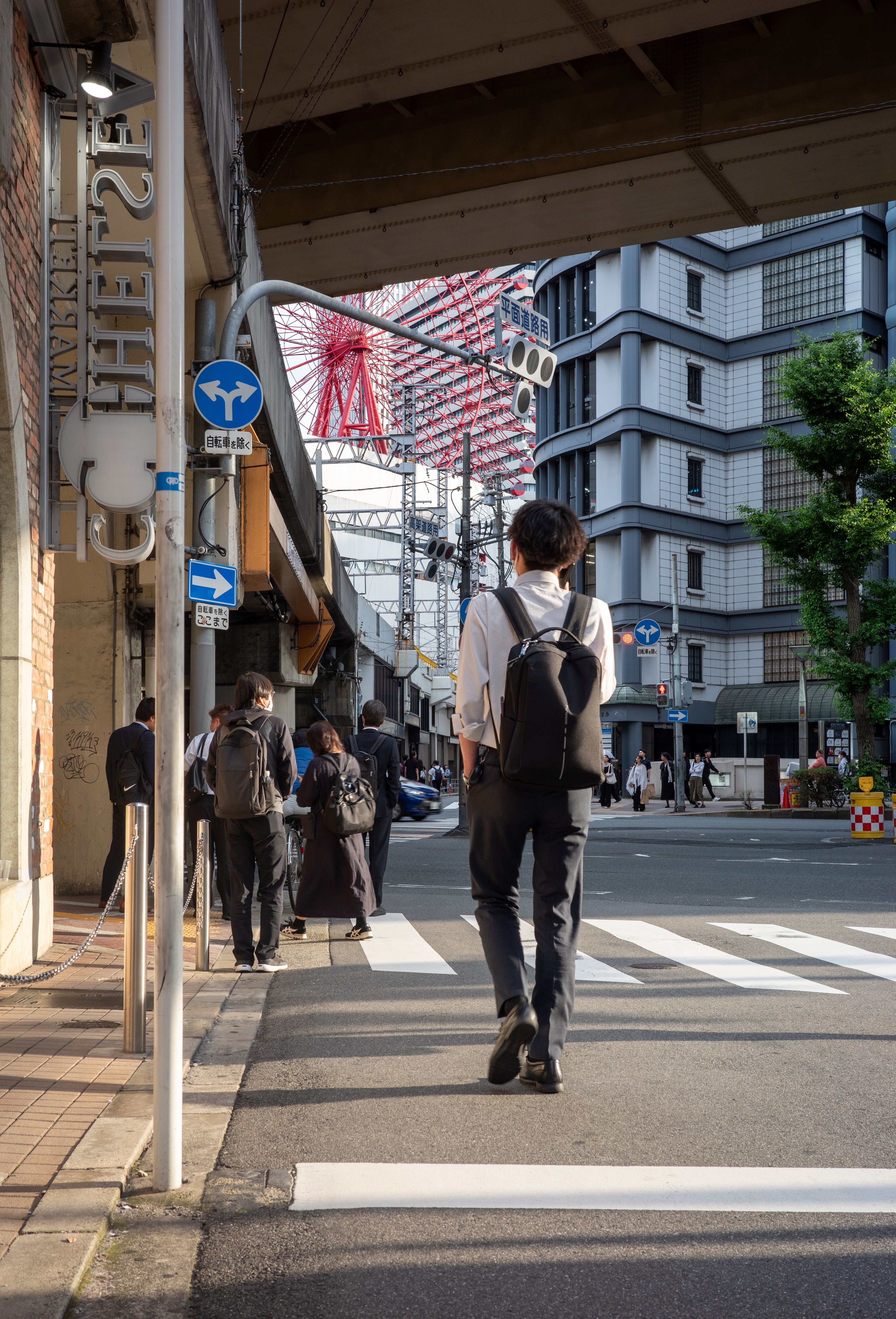 A pedestrian walks along a narrow sidewalk between shops.