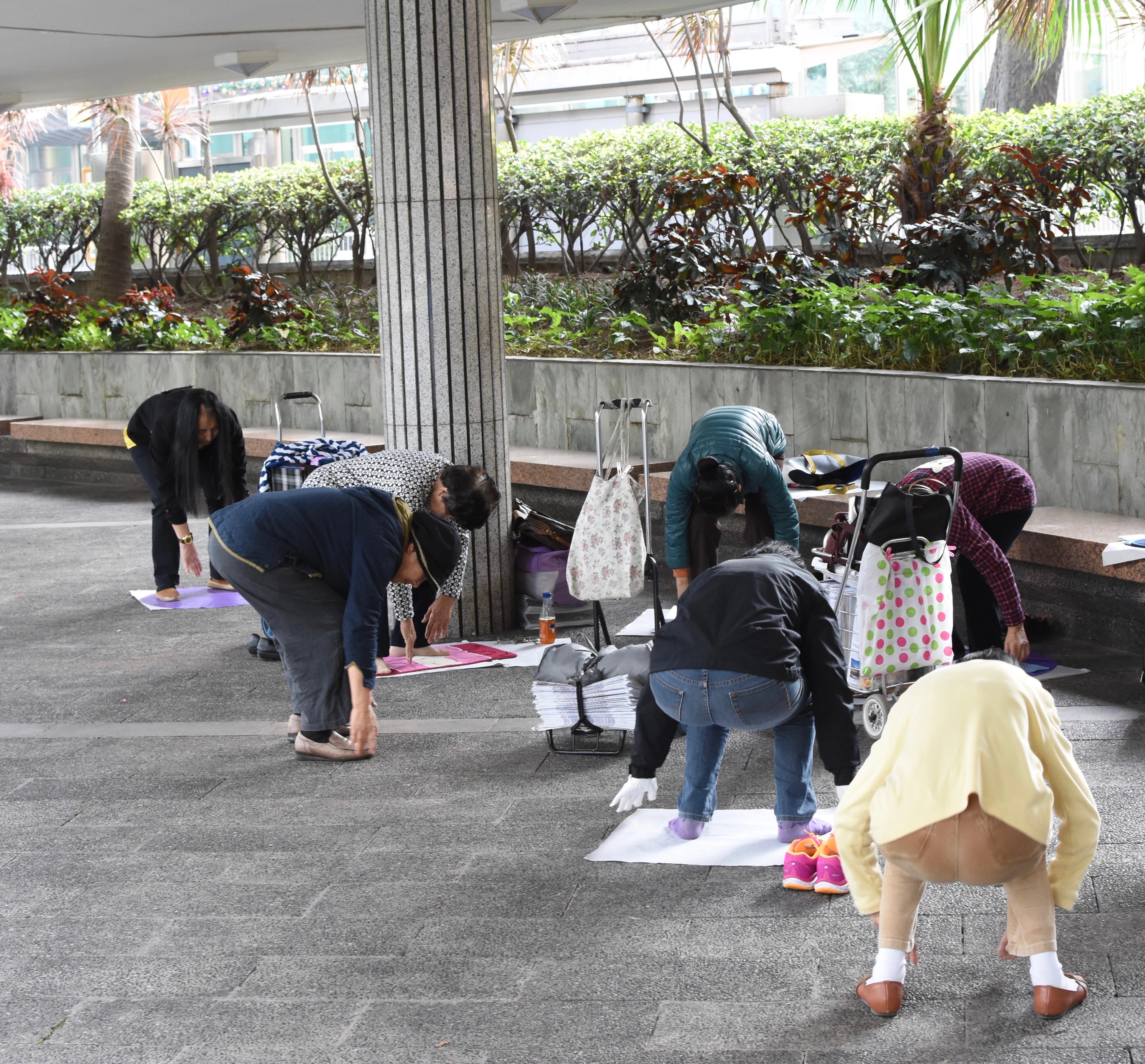 People crouch near a low railing beneath a covered walkway.