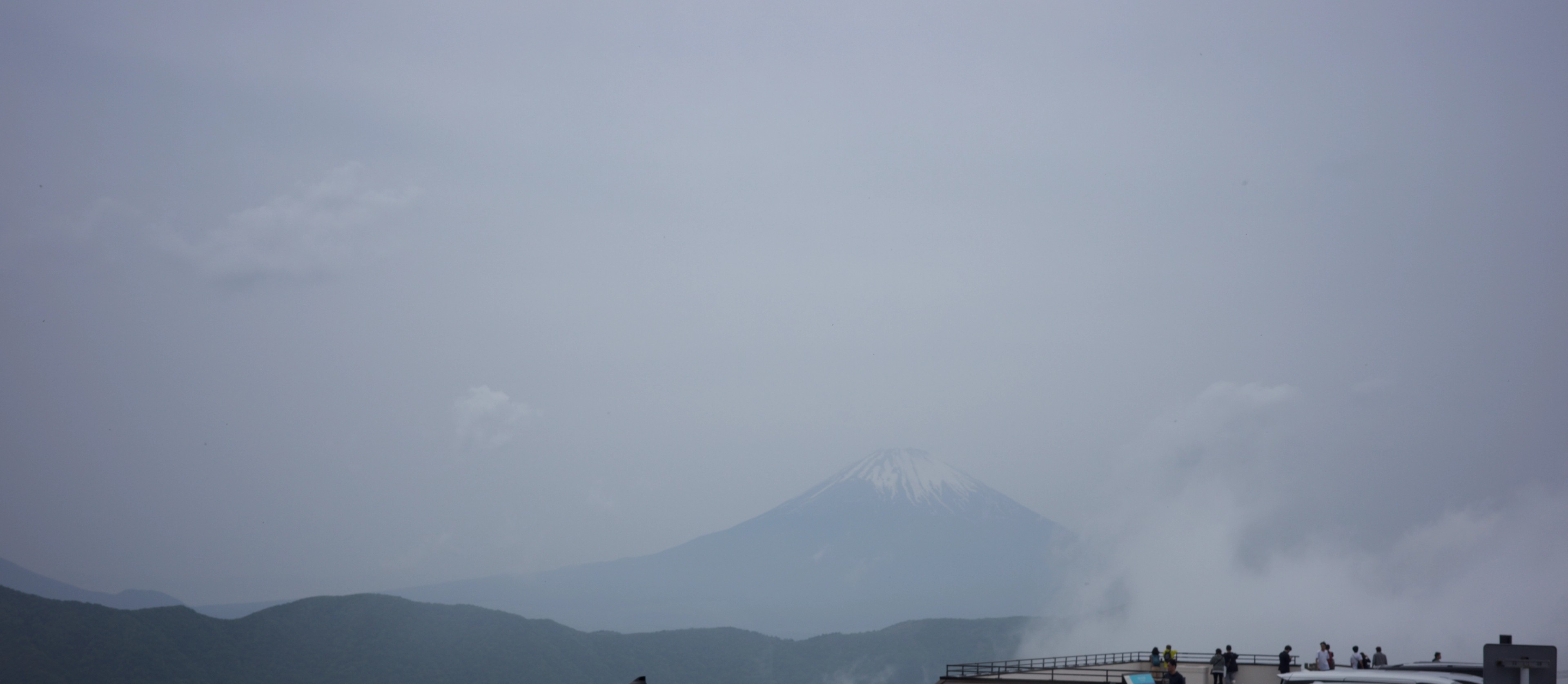 A hazy mountain sits beneath a cloudy sky.