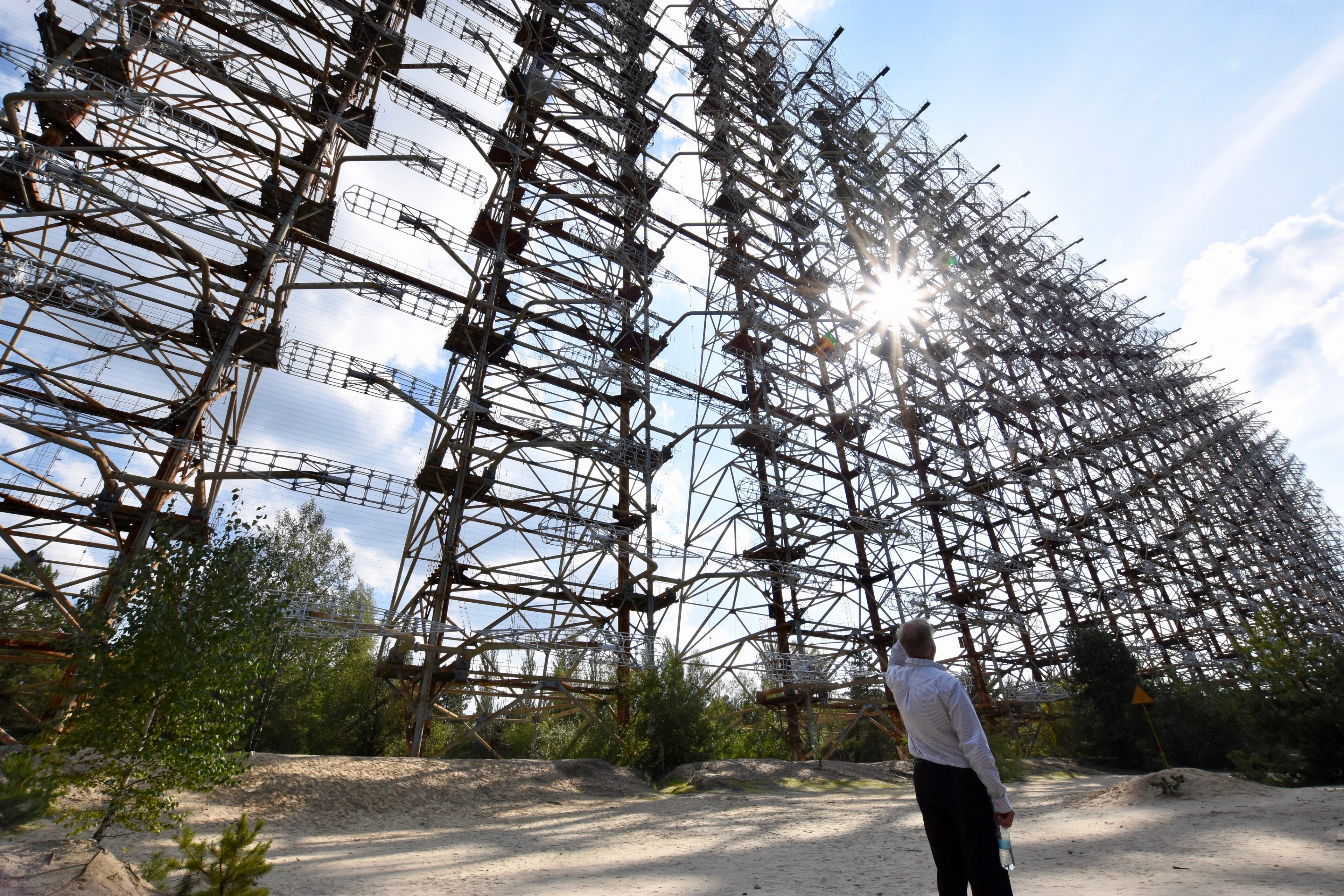 The steel framework of the Duga radar array rises above the trees.