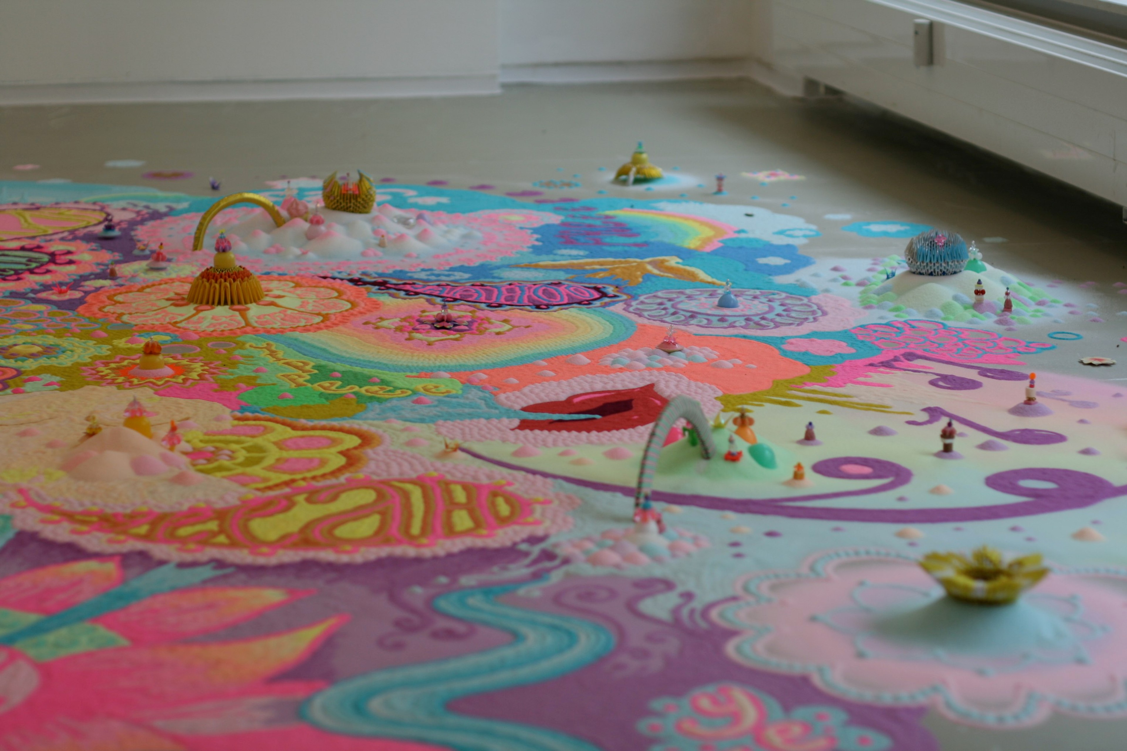 A brightly colored floor artwork fills a gallery room.