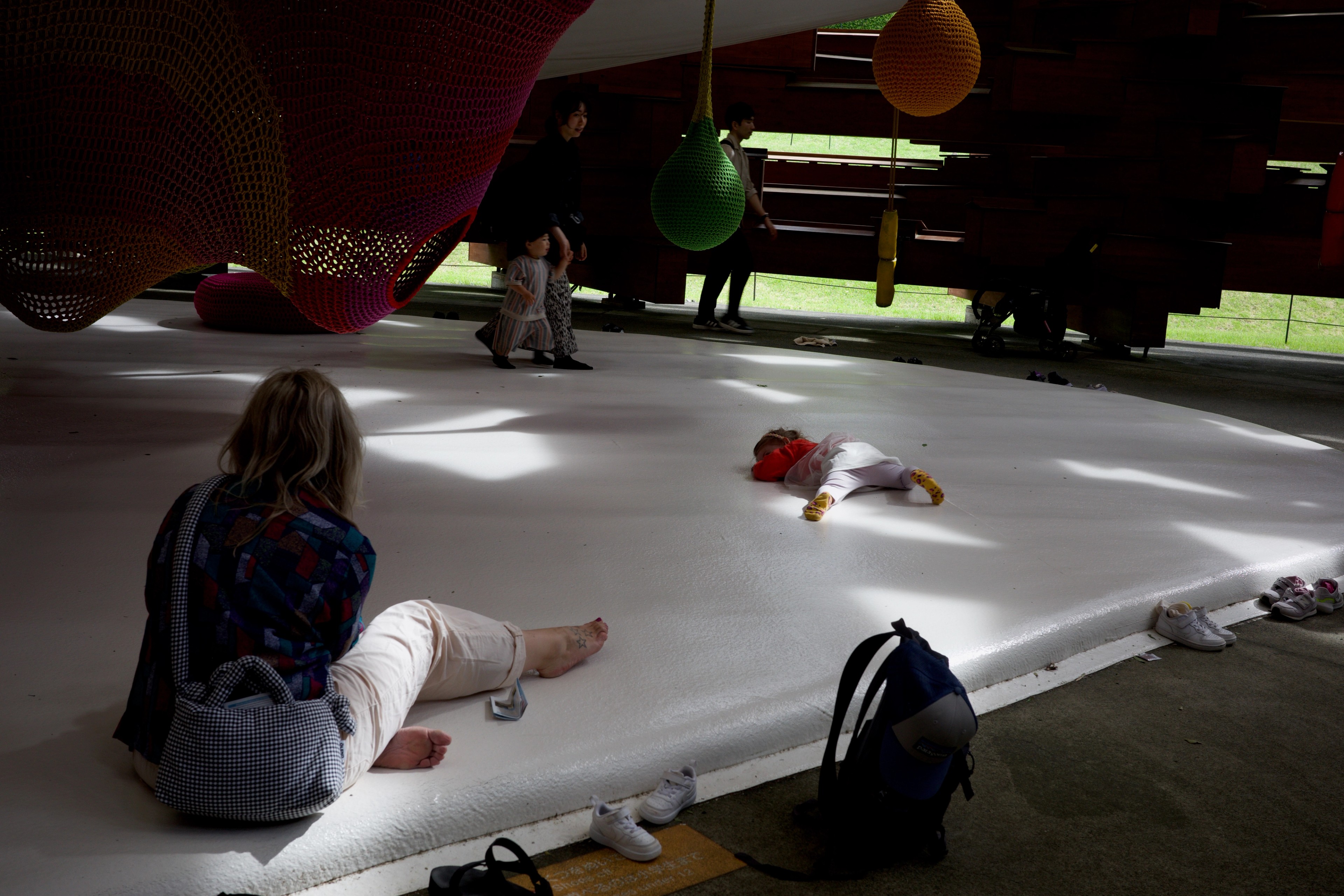 A seated adult watches a toddler crawl across a polished floor.