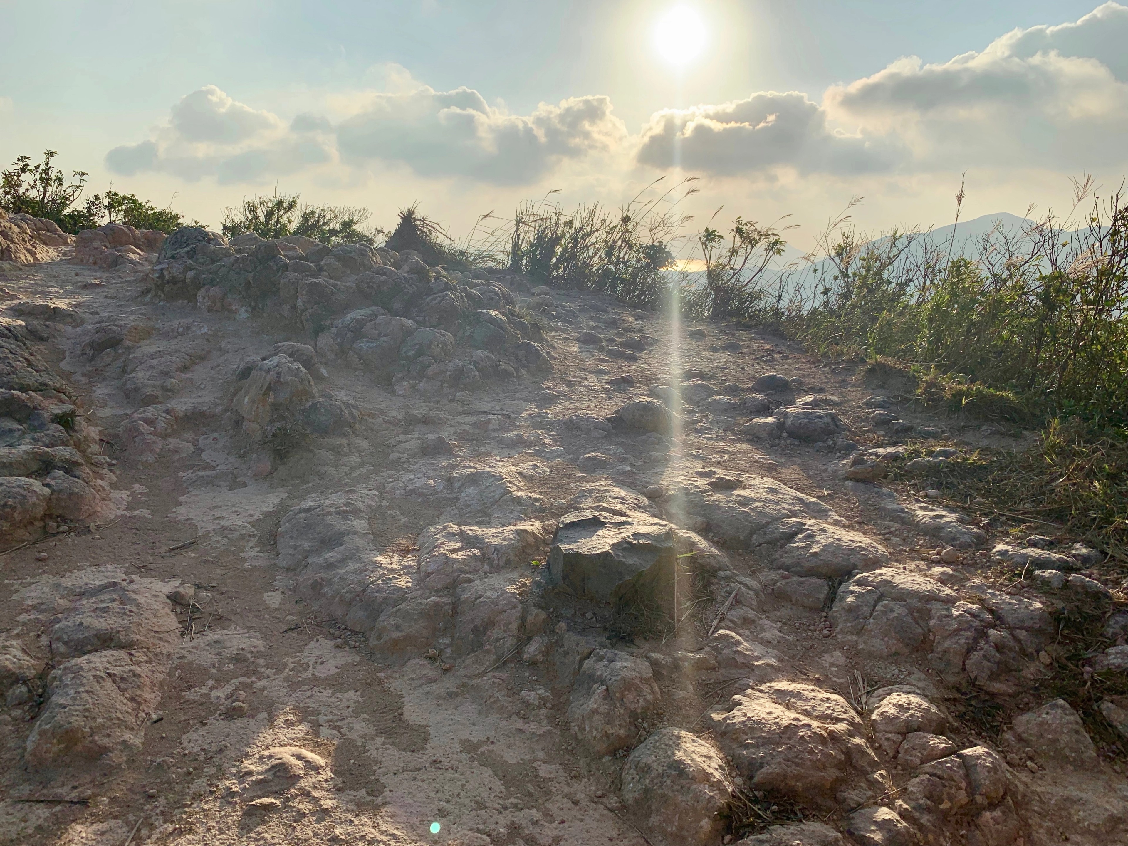 Sunlit rocky trail across the green Dragon’s Back ridge.
