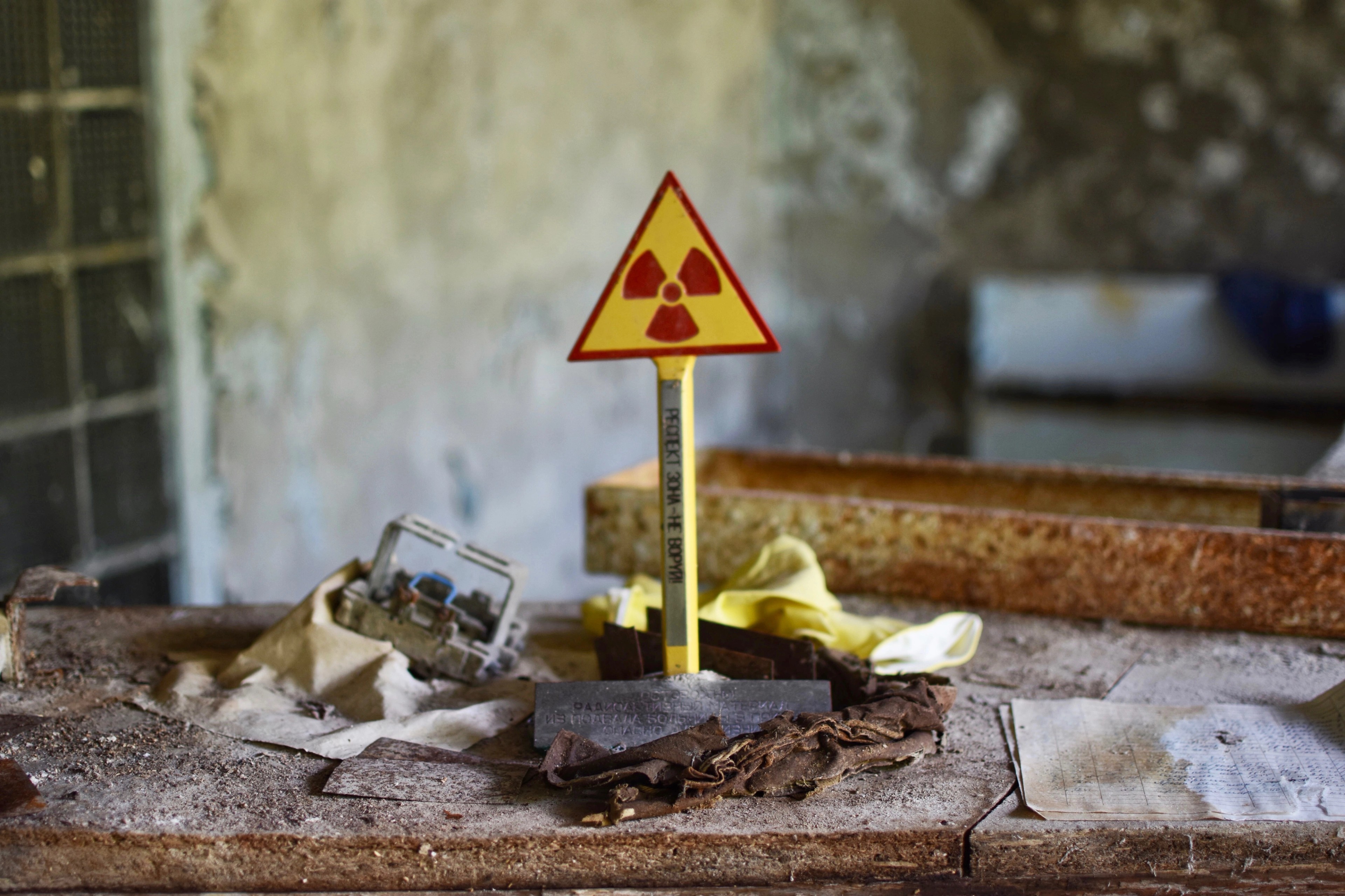 A small yellow radiation warning sign stands on a desk amid debris.