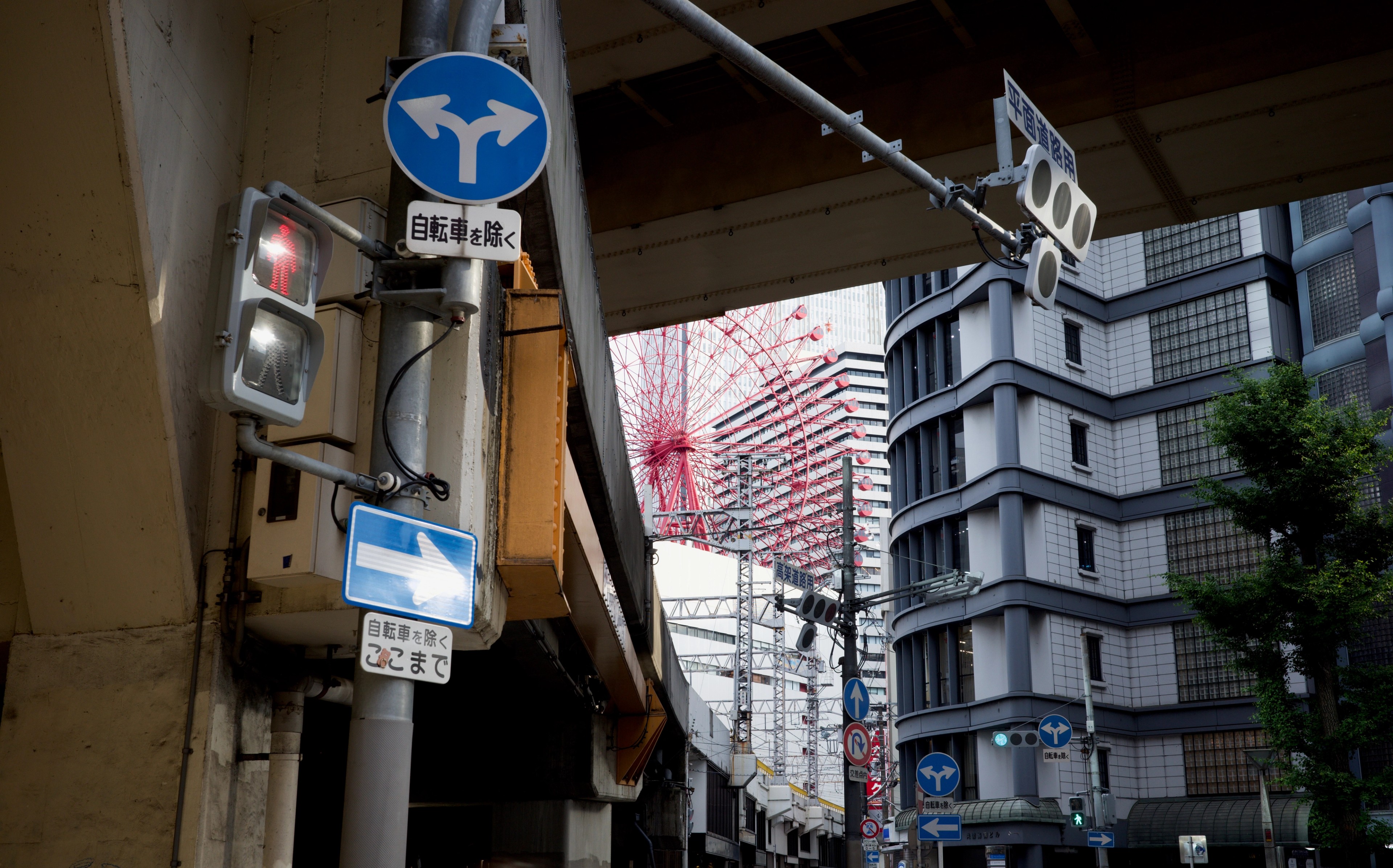 Street signs and tall buildings seen from beneath an awning.