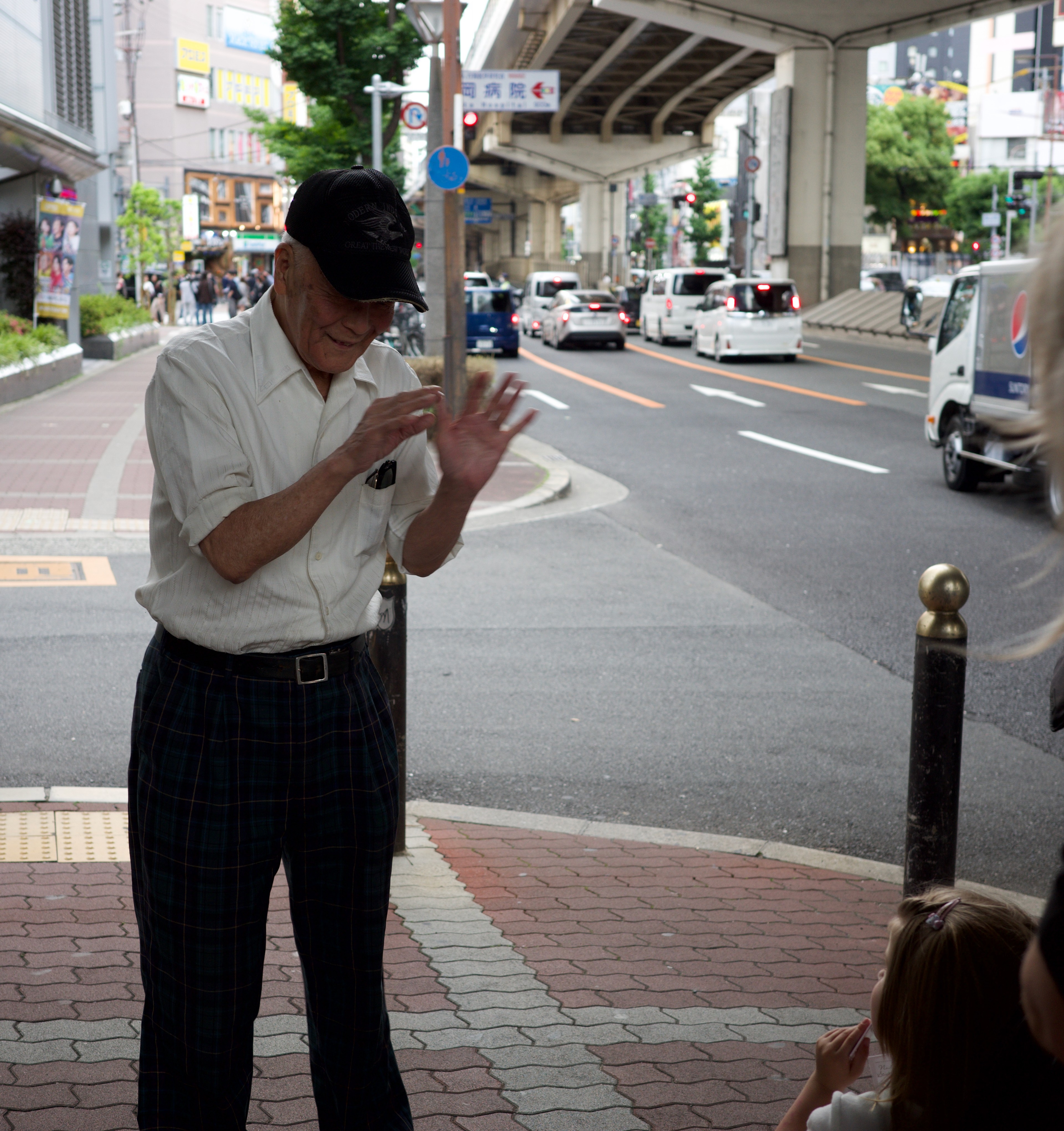 A man checks his phone beside a city sidewalk.