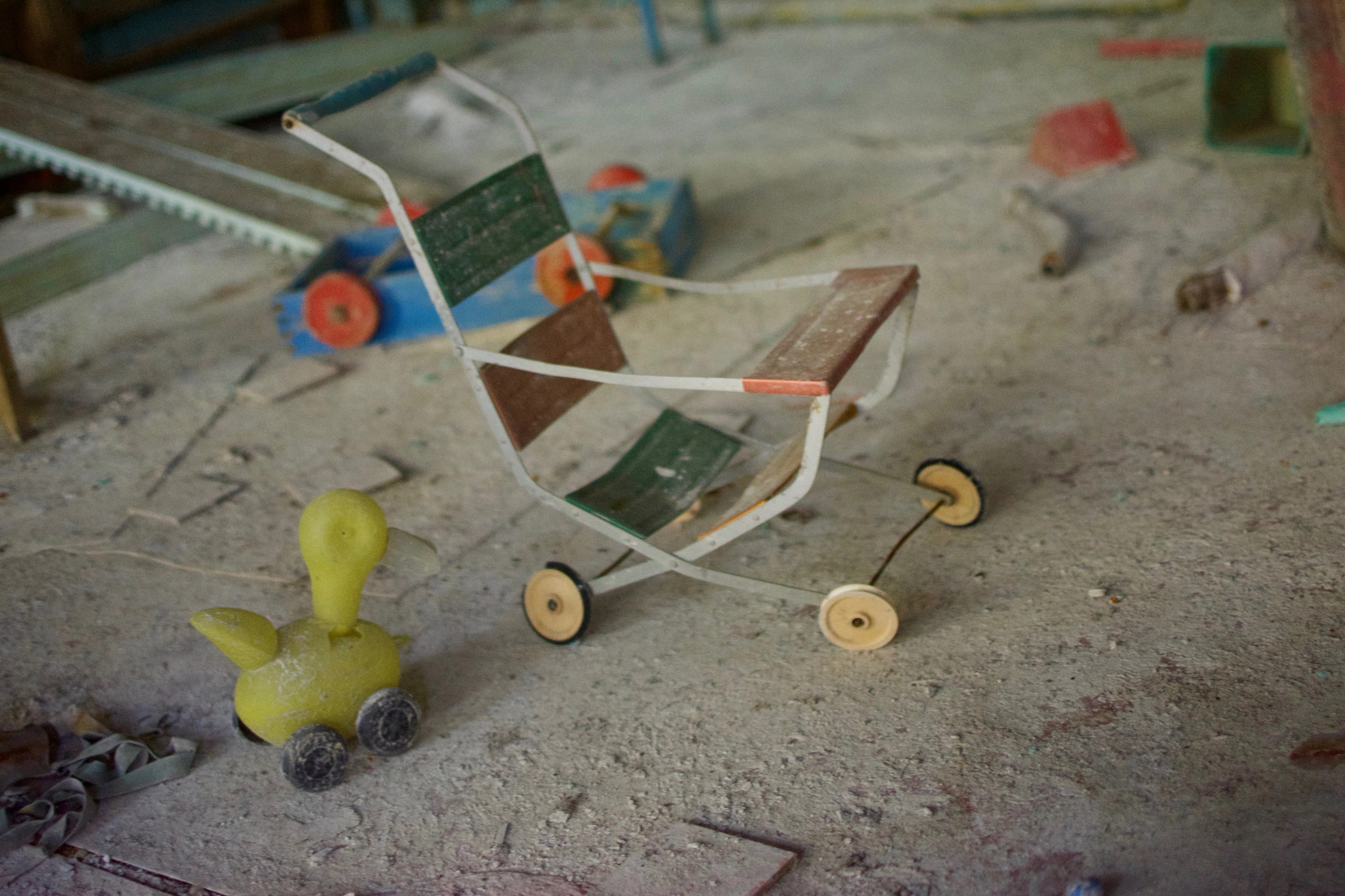 A toy stroller and ball lie on a dusty floor.