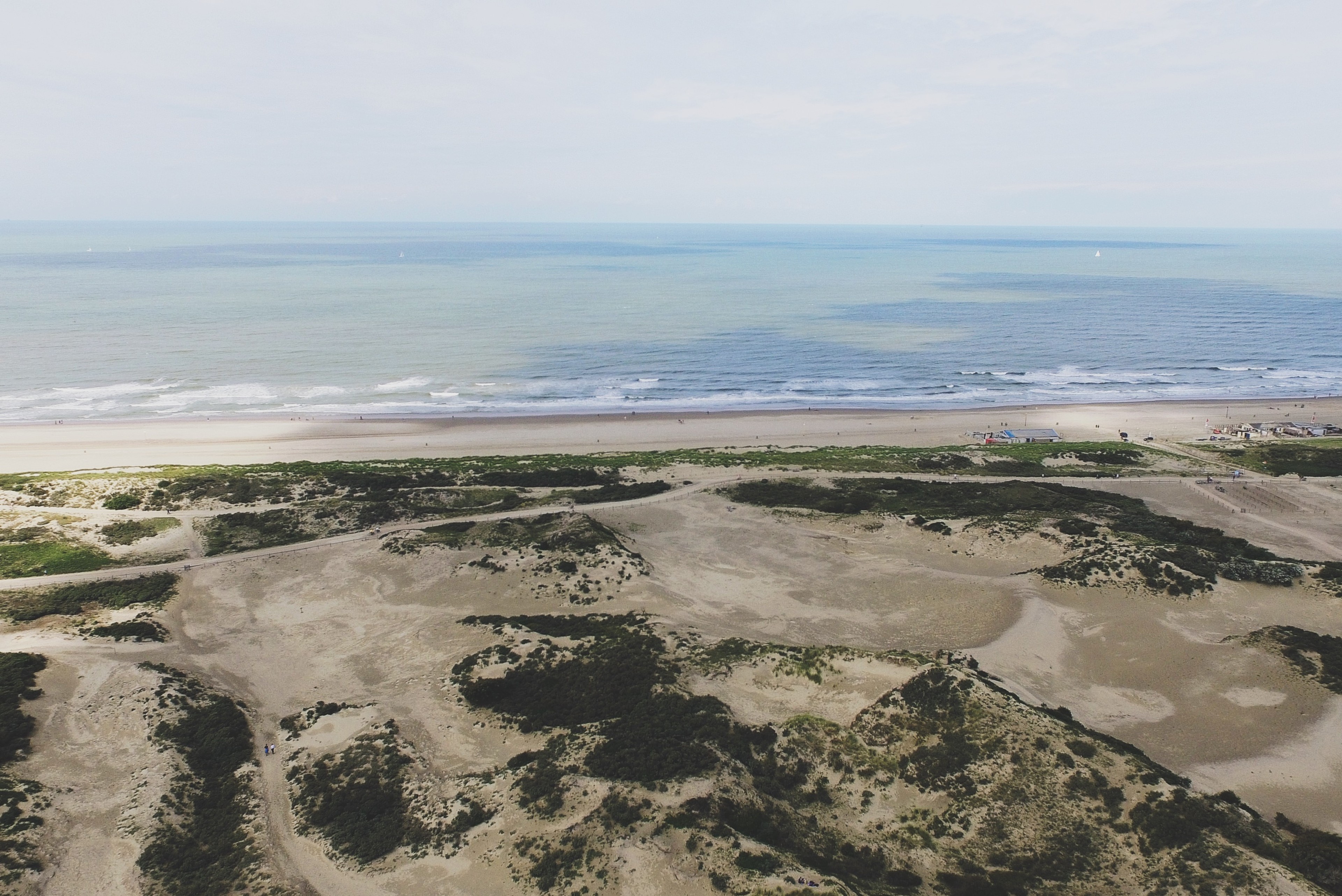 Aerial view of pale dunes and a beach beside the sea.