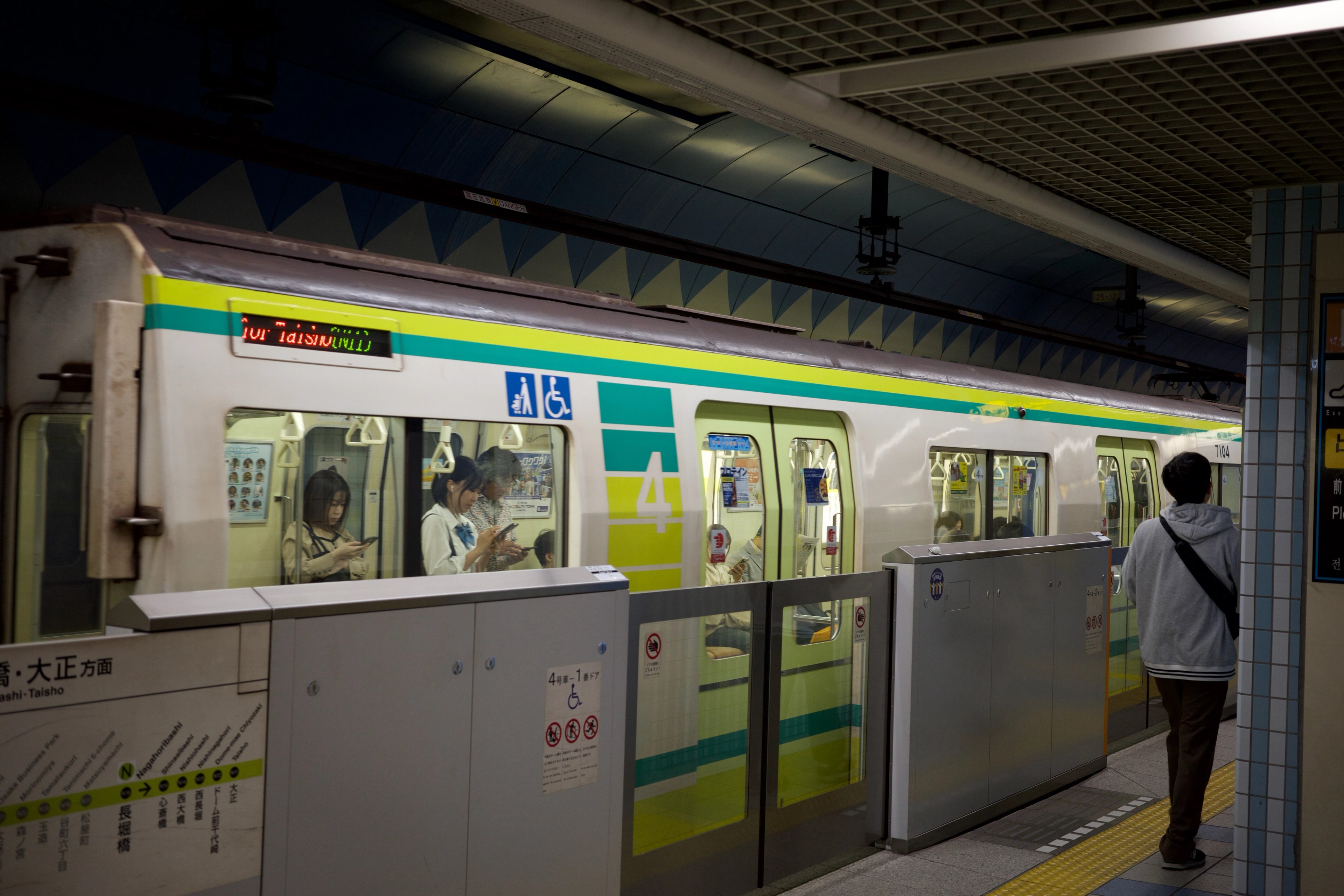 A green train is stopped at a station platform.