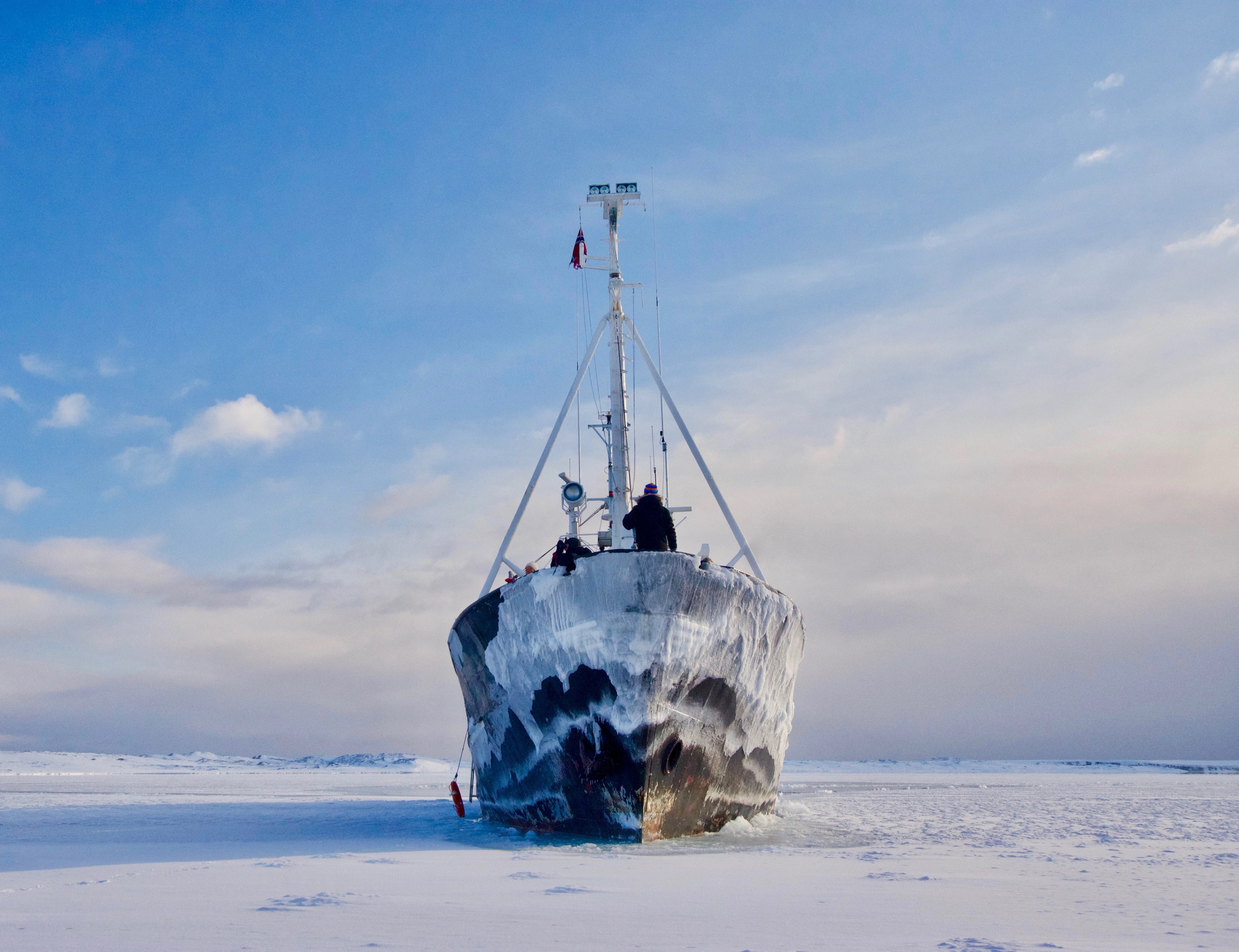 A ship stands frozen in a bright snow-covered landscape.